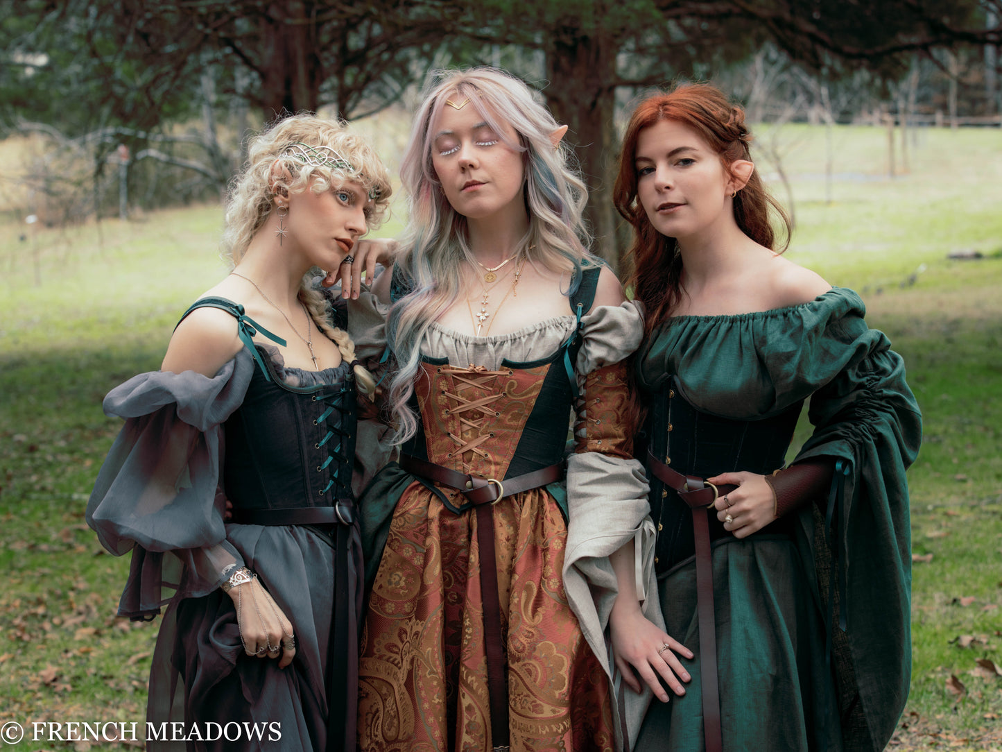 Three models wearing medieval fantasy costumes, featuring the Grey Chiffon Chemise with corsets and period dresses