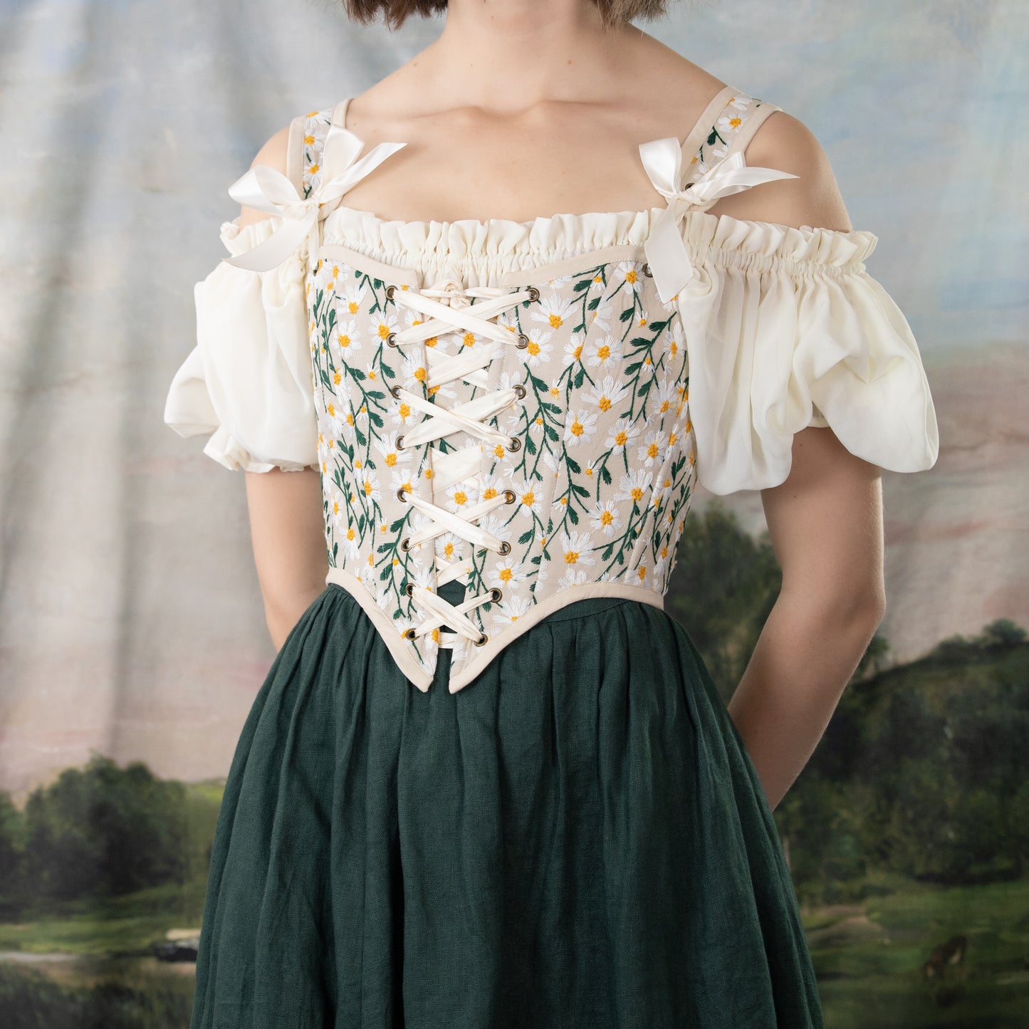 Embroidered Daisies Corset Top with off-shoulder puff sleeves, floral embroidery and lace-up front on cream bodice with green skirt