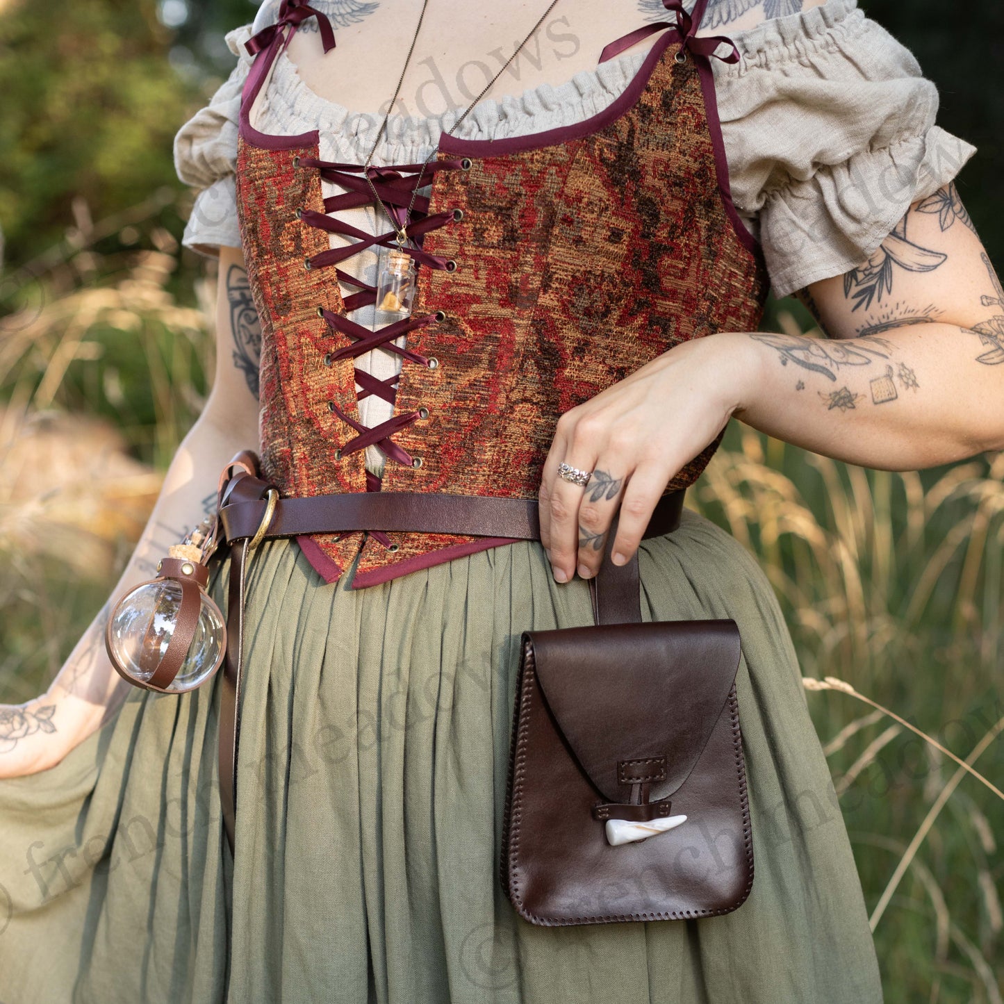 Brown leather belt pouch shown on renaissance outfit with burgundy corset and olive green skirt, attached at waist