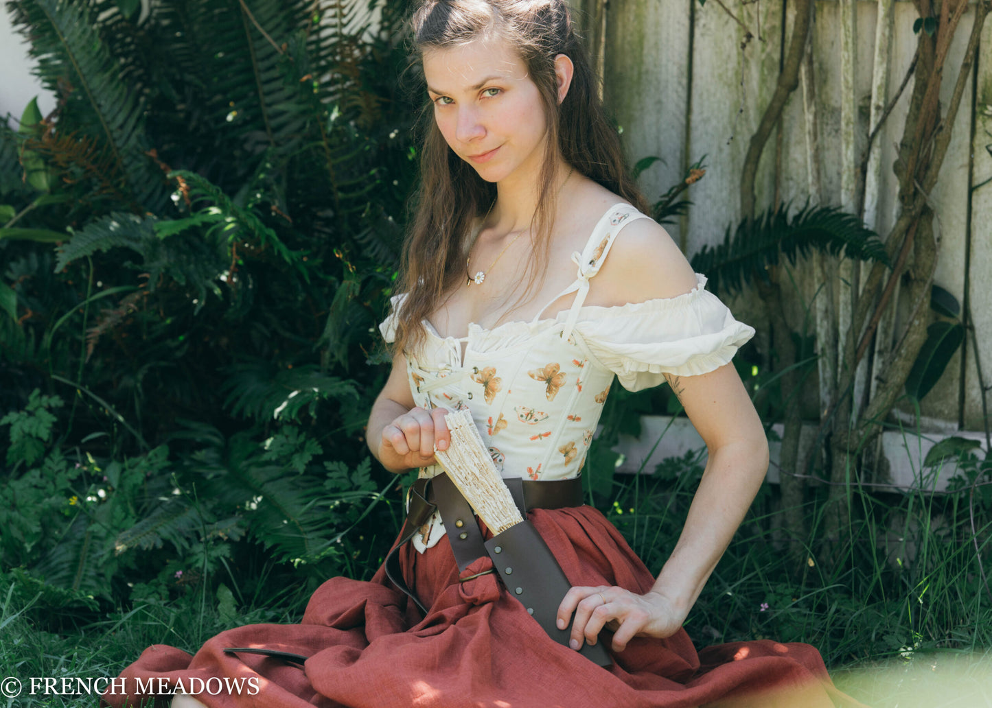 Renaissance Fan Holster shown on brown leather belt with off-shoulder floral dress in garden setting