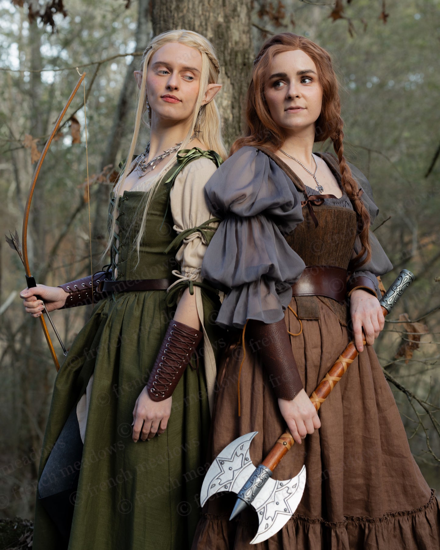Two models in medieval fantasy costumes showcase Brown Tabbed Tudor Stays with matching weapons in a forest setting