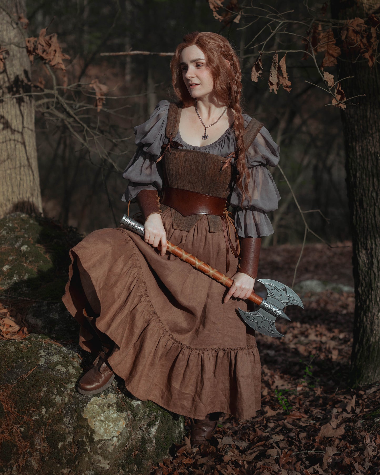 Brown Tabbed Tudor Stays worn with medieval dress and decorative armor in autumn forest setting, model holding battle axe