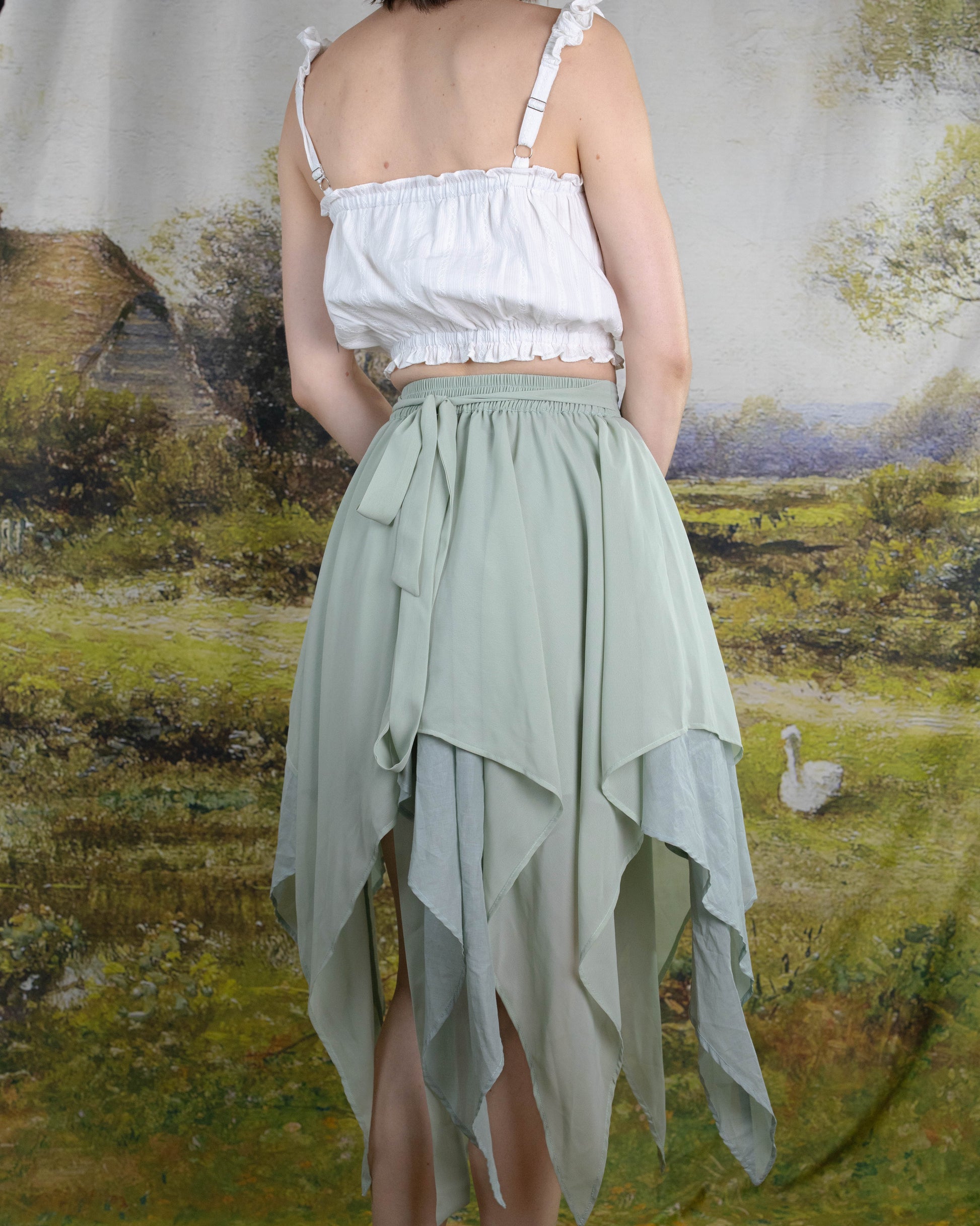 Back view of a woman wearing a pale green layered handkerchief hem Flower Fairy Skirt with elastic waist and ties