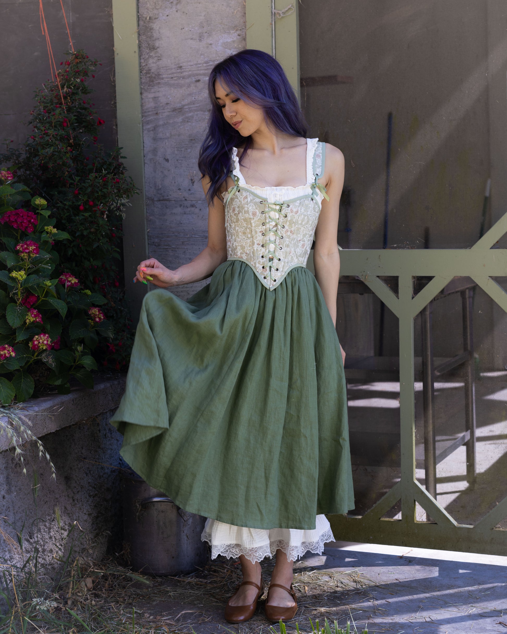Woman wearing a light green jacquard corset top with floral patterns and adjustable lace-up details outdoors