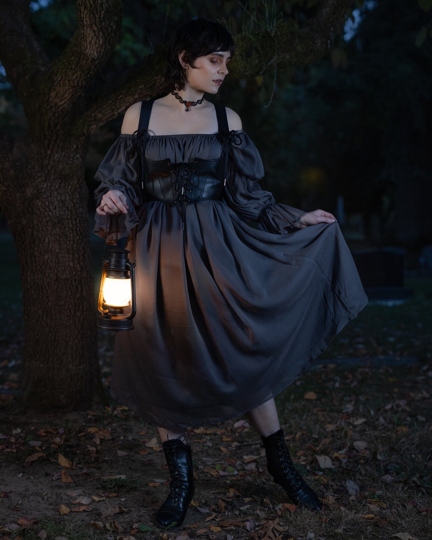 Grey Chiffon Chemise shown in dark forest setting with lantern light, off-shoulder design and corset details at dusk