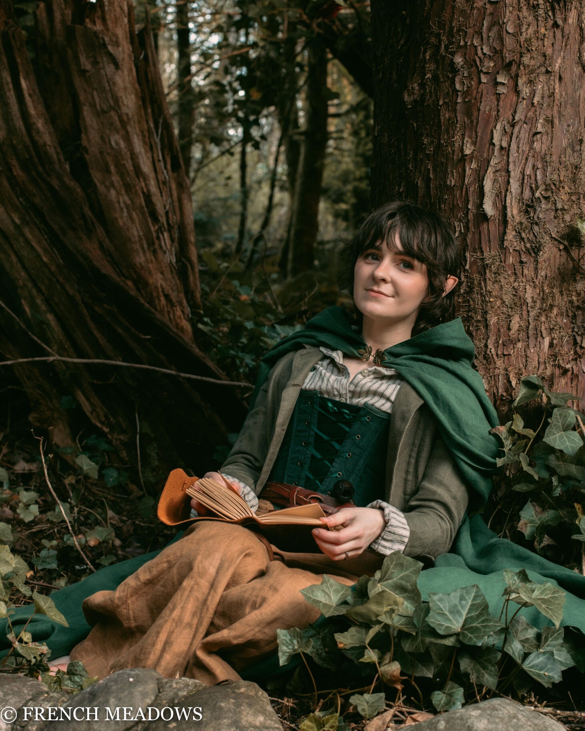 Linen Renaissance Cloak shown in enchanted forest setting, with forest backdrop and ivy, displaying medieval-inspired design