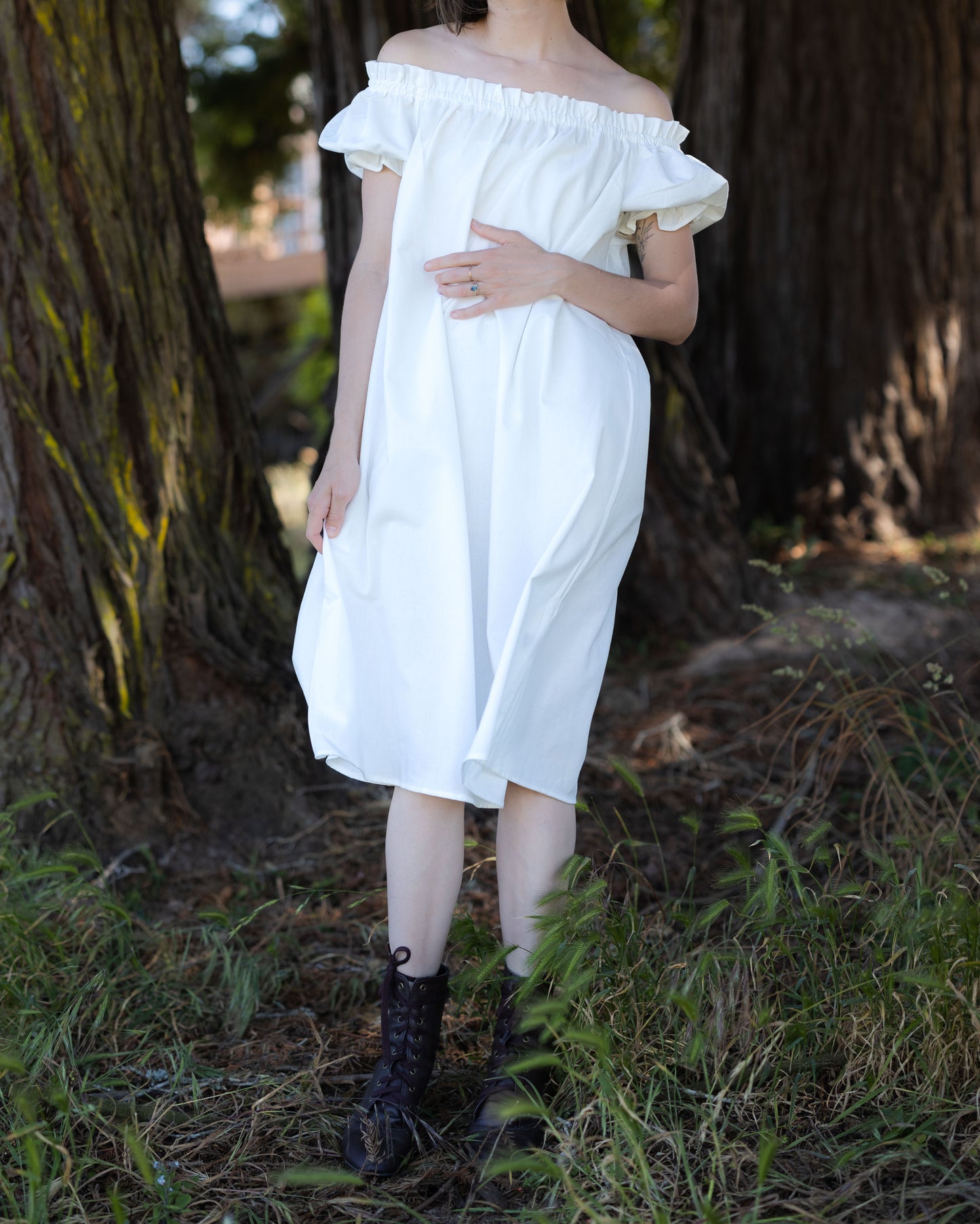 Woman wearing Ivory Short Sleeve Linen Chemise with off-the-shoulder neckline and puff sleeves outdoors by trees.