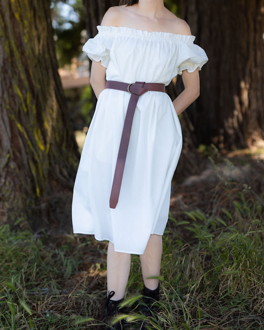 Ivory Short Sleeve Linen Chemise worn off-shoulder with ruffled neckline and puff sleeves, styled with a brown belt outdoors.
