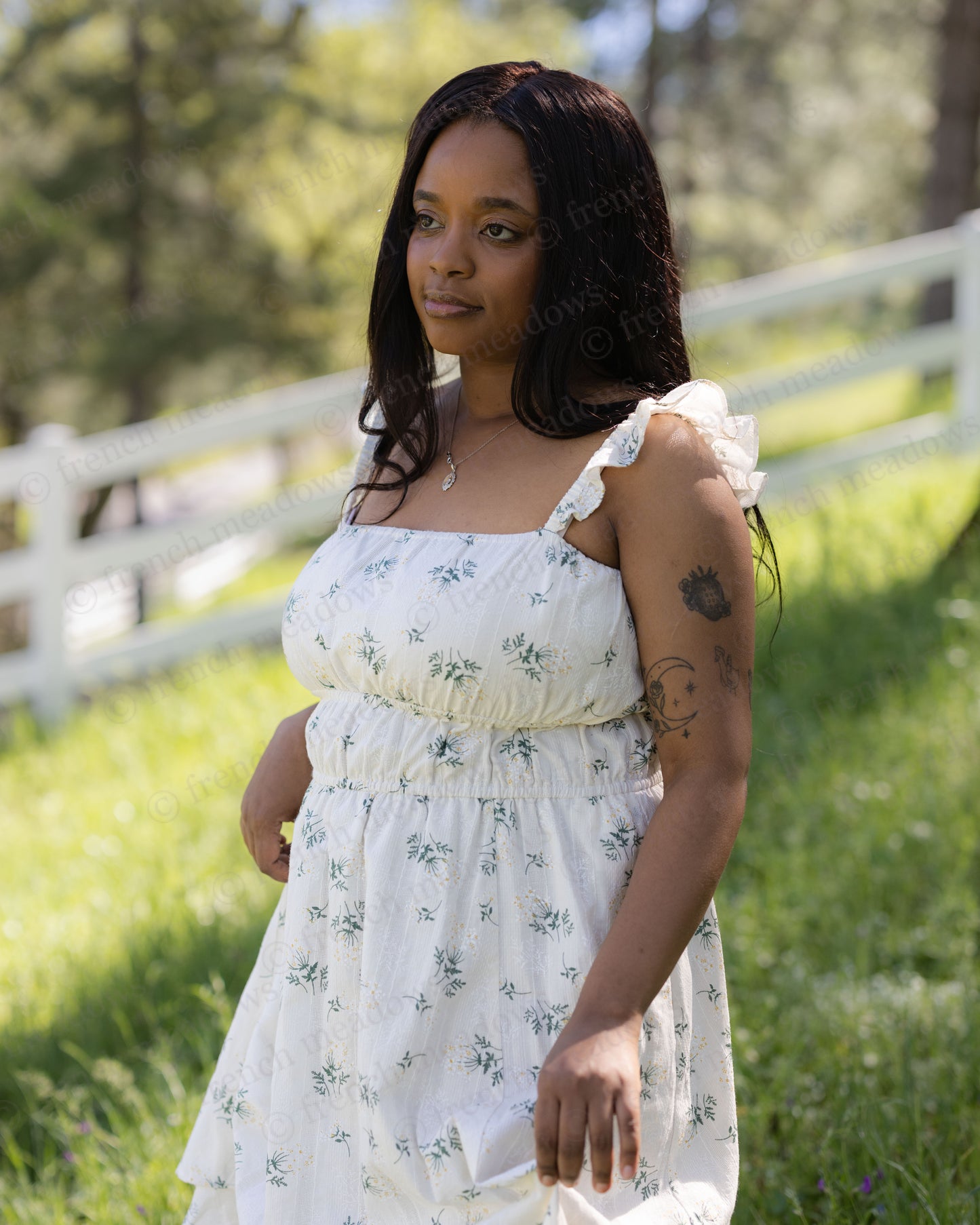 Woman wearing a white Floral Milkmaid Dress with ruched bodice and square neckline standing outdoors in sunlight