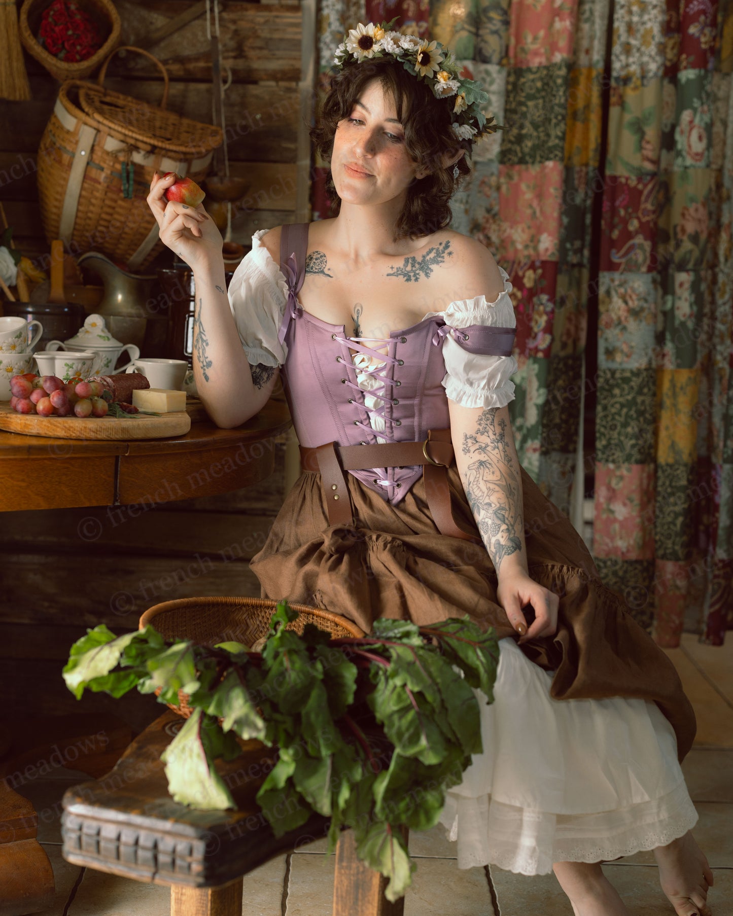 Purple Dusk Satin Corset Top styled in cottage core setting with flower crown, ruffled skirt, and vintage table setting with fruit