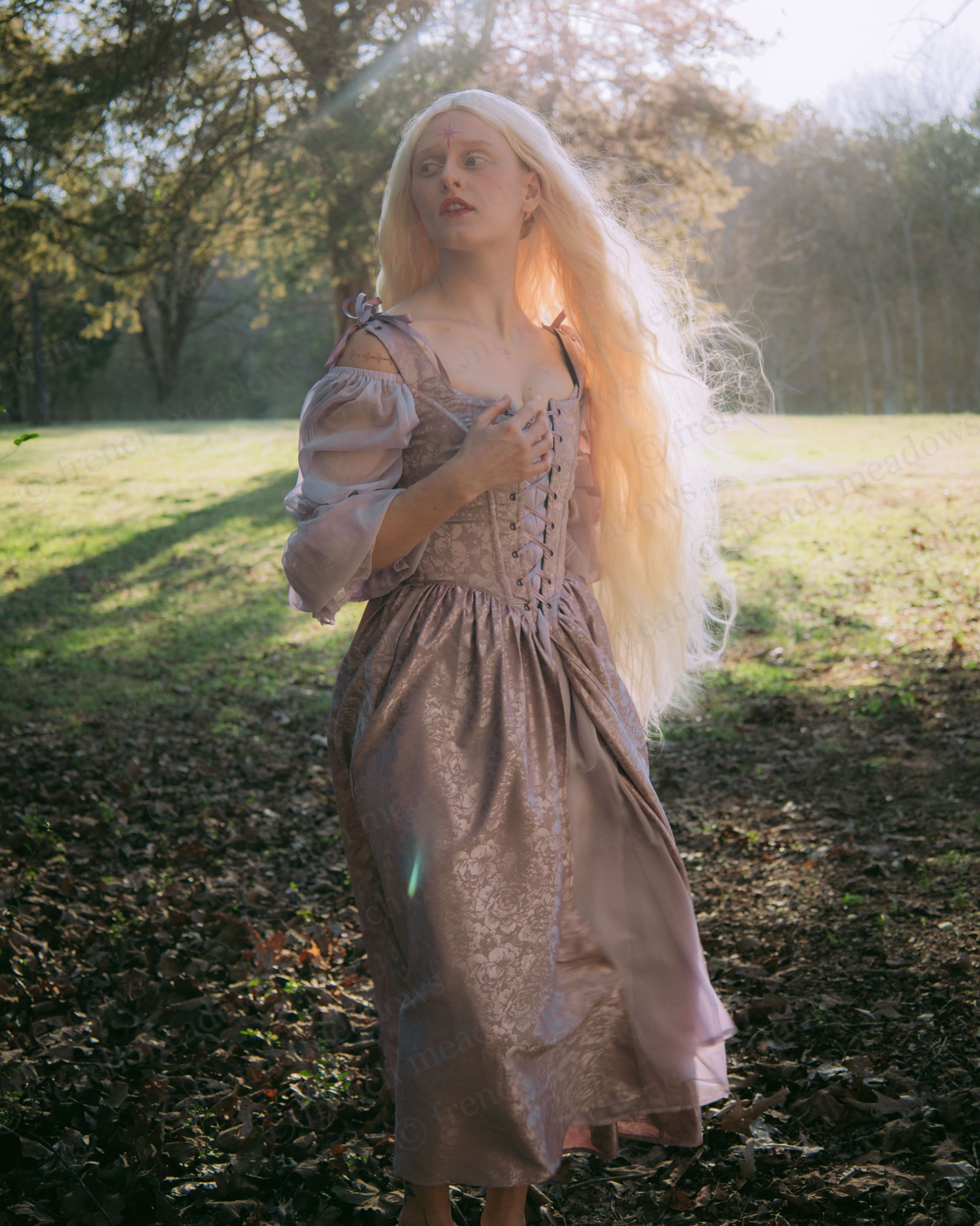 Lavender Floral Satin Corset Dress shown in ethereal outdoor setting with sunlit forest backdrop, highlighting shimmering fabric texture
