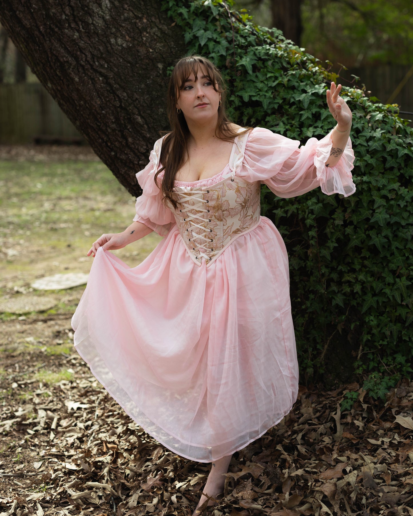 Pink and Gold Metallic Floral Corset Top shown in outdoor setting with Renaissance-style design featuring delicate gold embroidery and billowing sleeves
