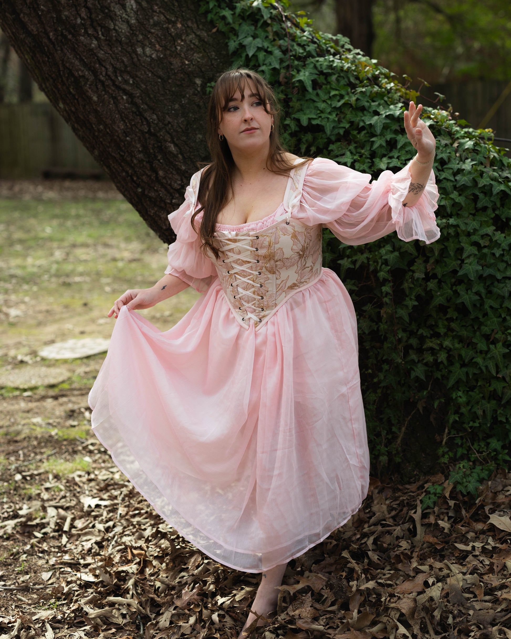 Pink and Gold Metallic Floral Corset Top shown in outdoor setting with Renaissance-style design featuring delicate gold embroidery and billowing sleeves