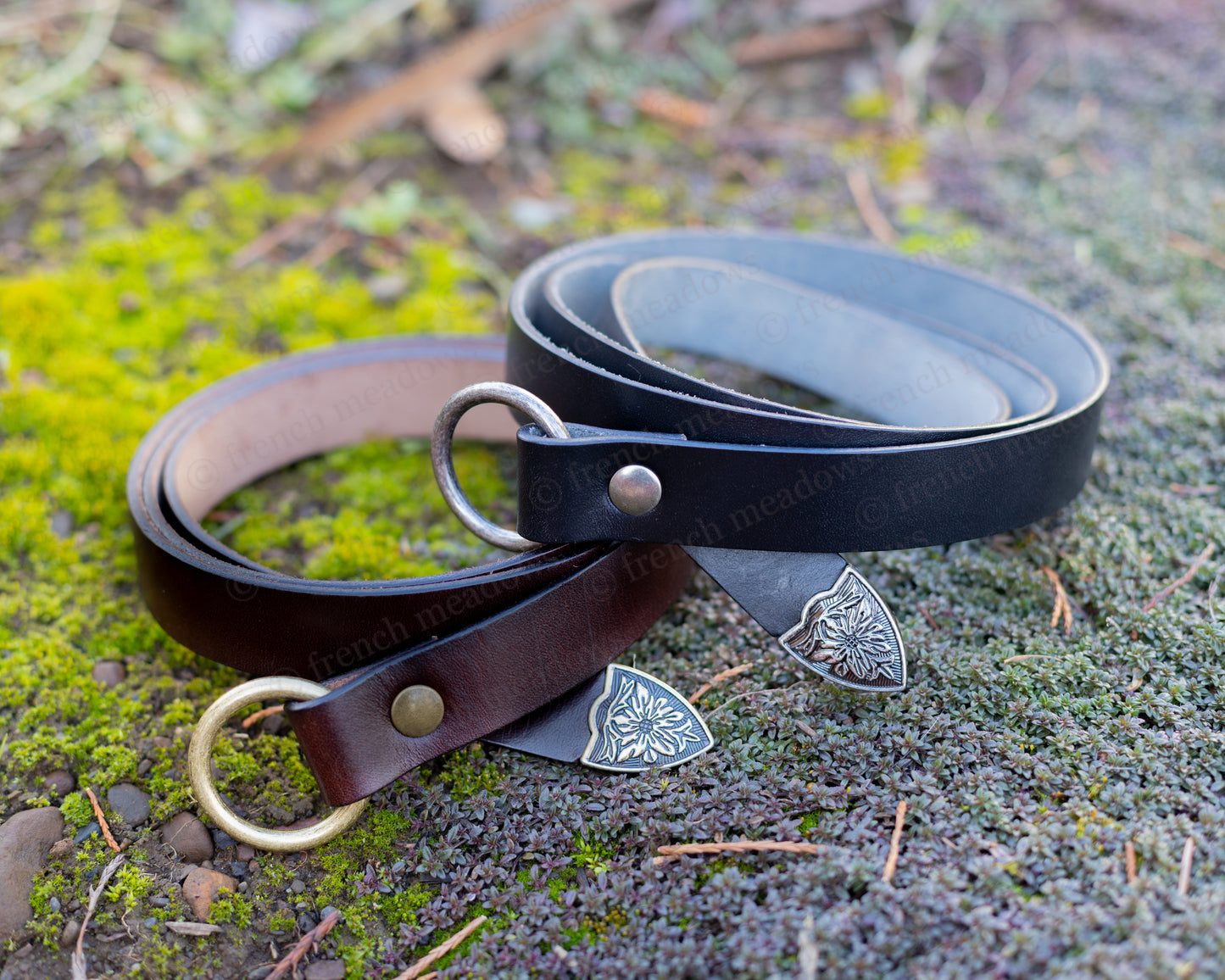 Leather Renaissance Belt in brown and black with decorative metal shield tips shown on mossy ground