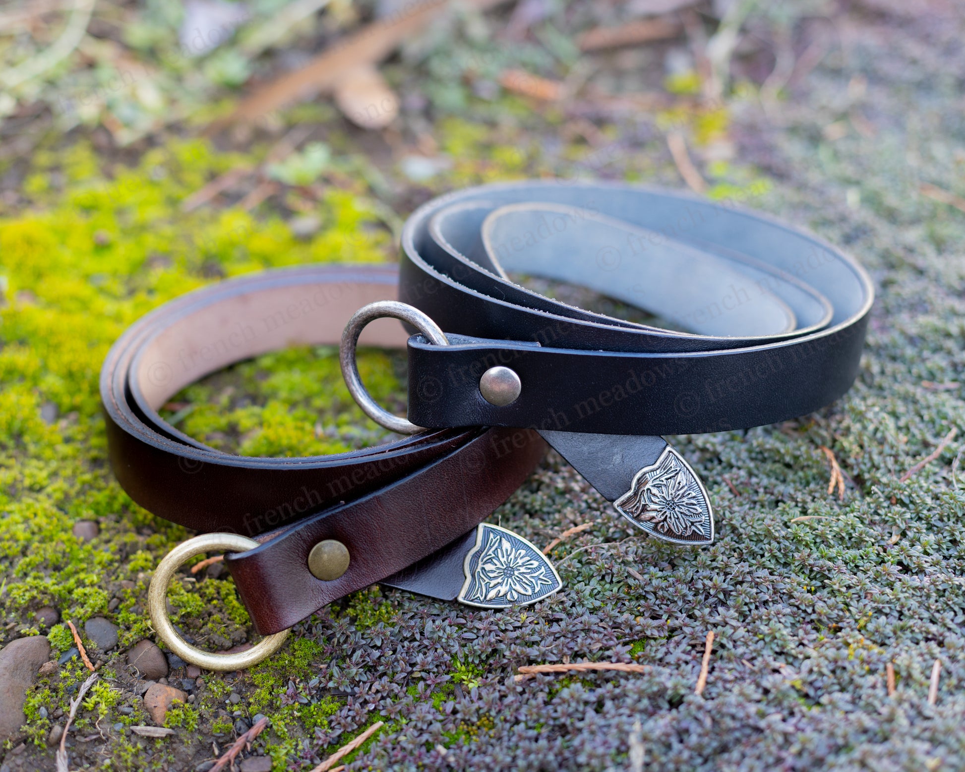 Leather Renaissance Belt in brown and black with decorative metal shield tips shown on mossy ground