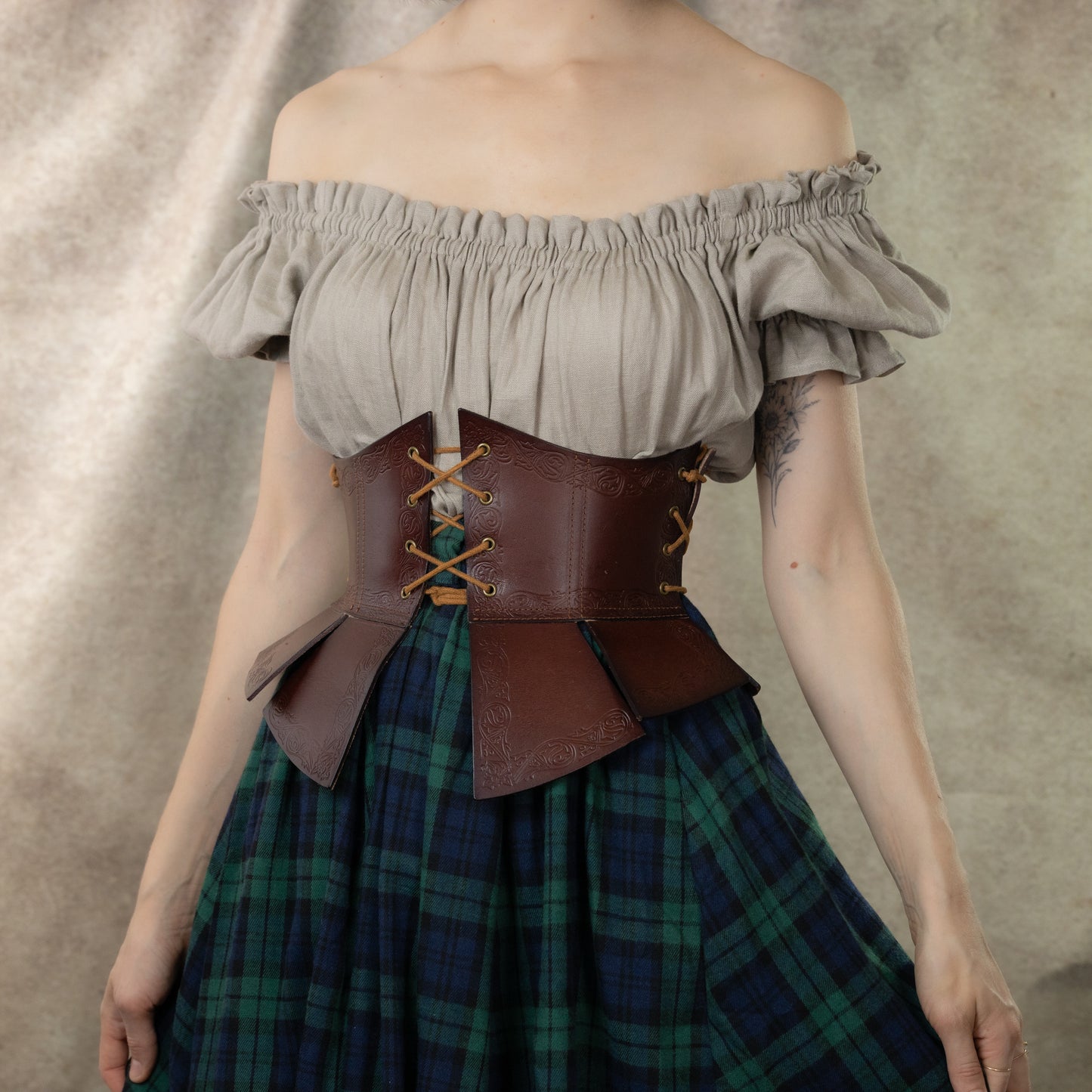 Debossed leather underbust corset with medieval pattern shown with peasant blouse and plaid skirt, creating medieval look