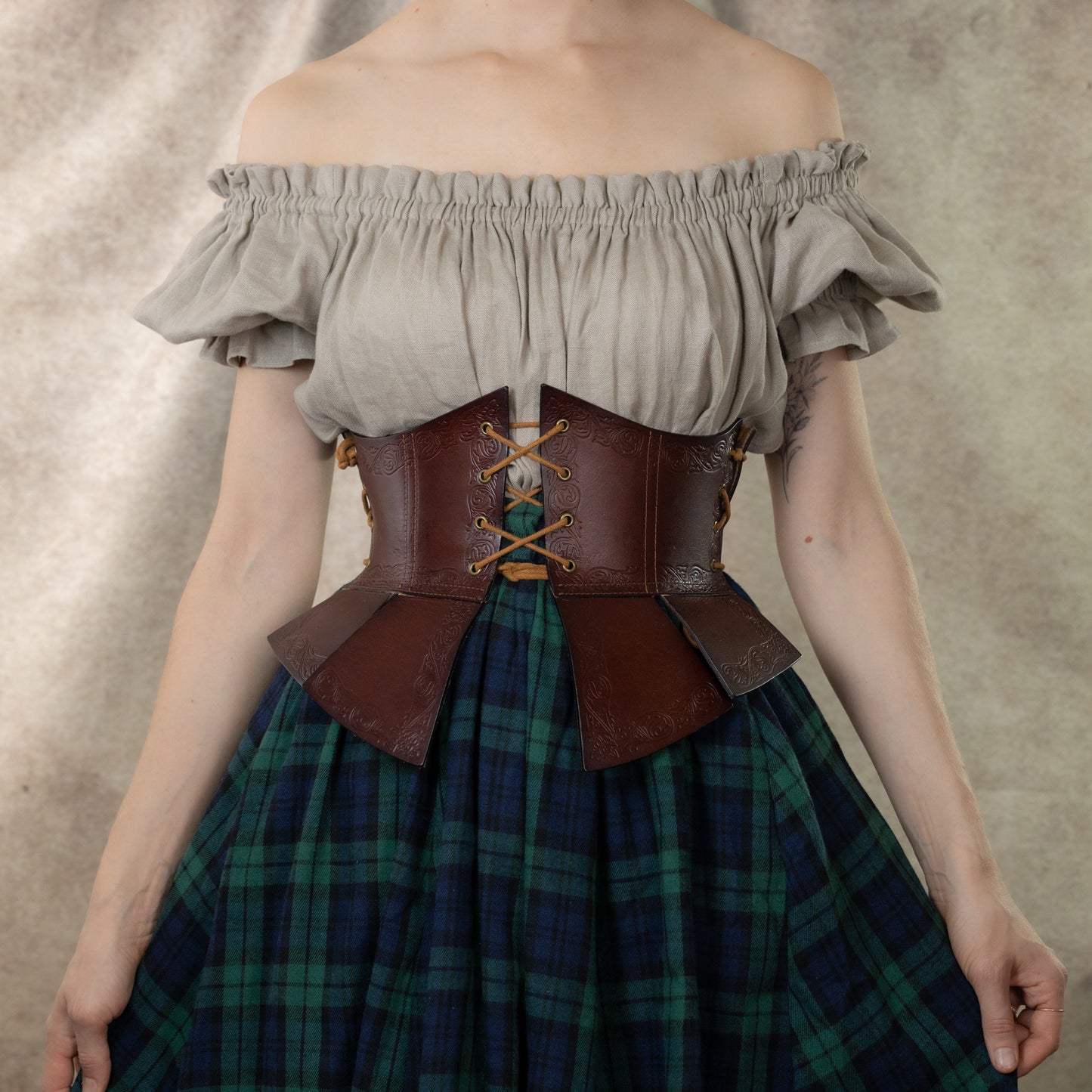 Debossed leather underbust corset with medieval pattern, paired with white peasant top and plaid skirt in green tartan