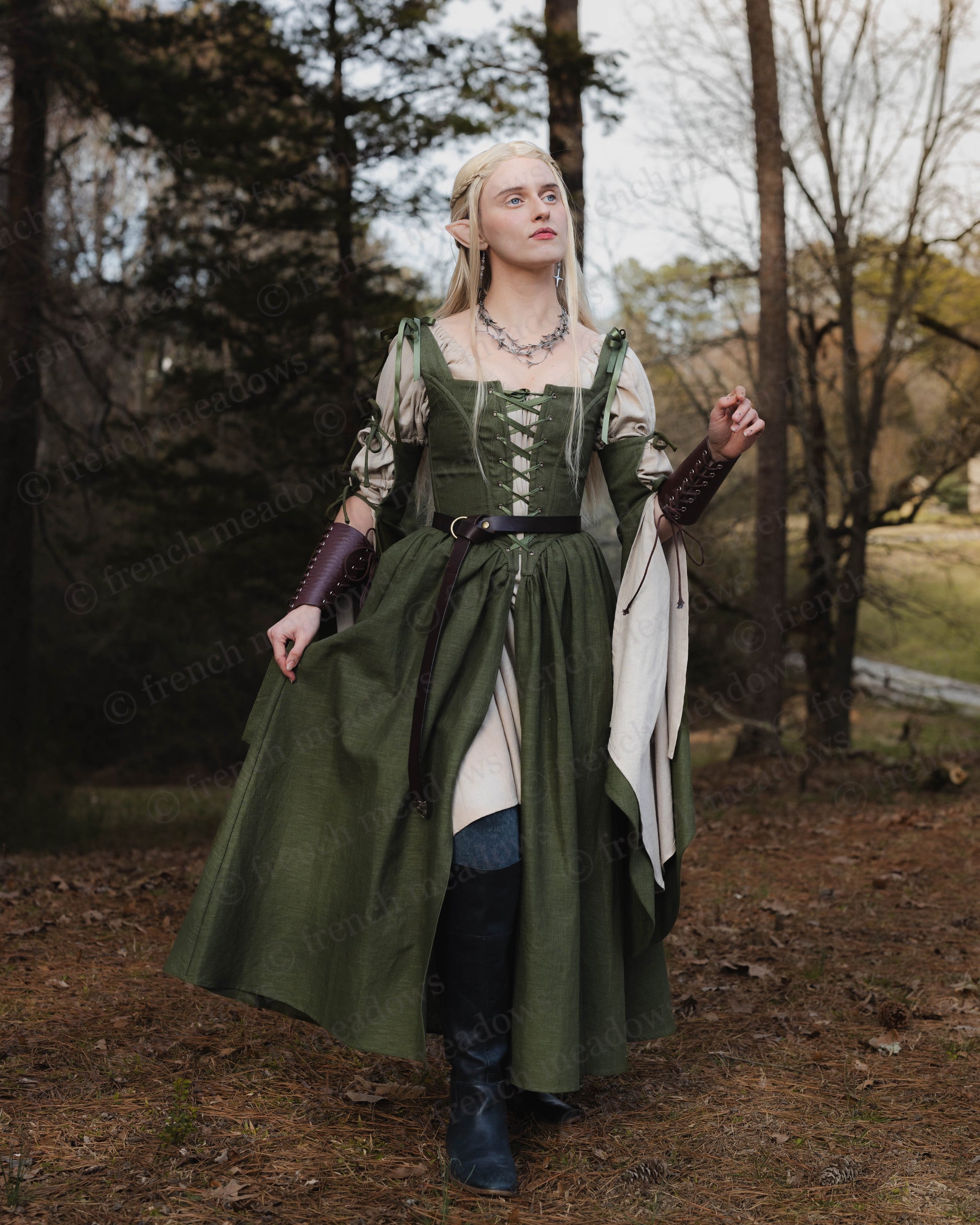 Ivy Green Corset Dress shown in woodland setting with flowing medieval design, laced bodice and bell sleeves