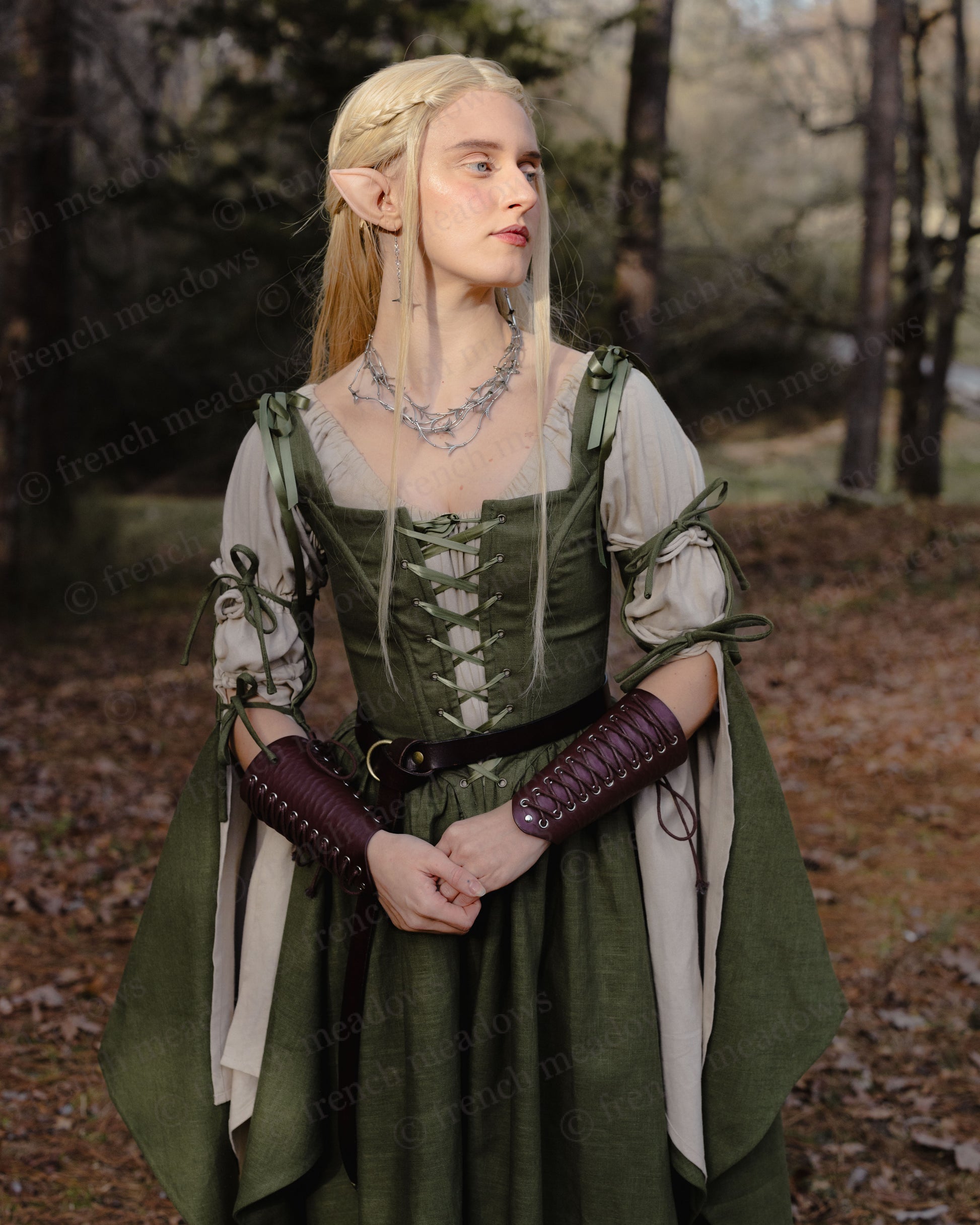 Ivy Green Corset Dress shown with laced bodice, flowing bell sleeves, and medieval fantasy styling in forest setting