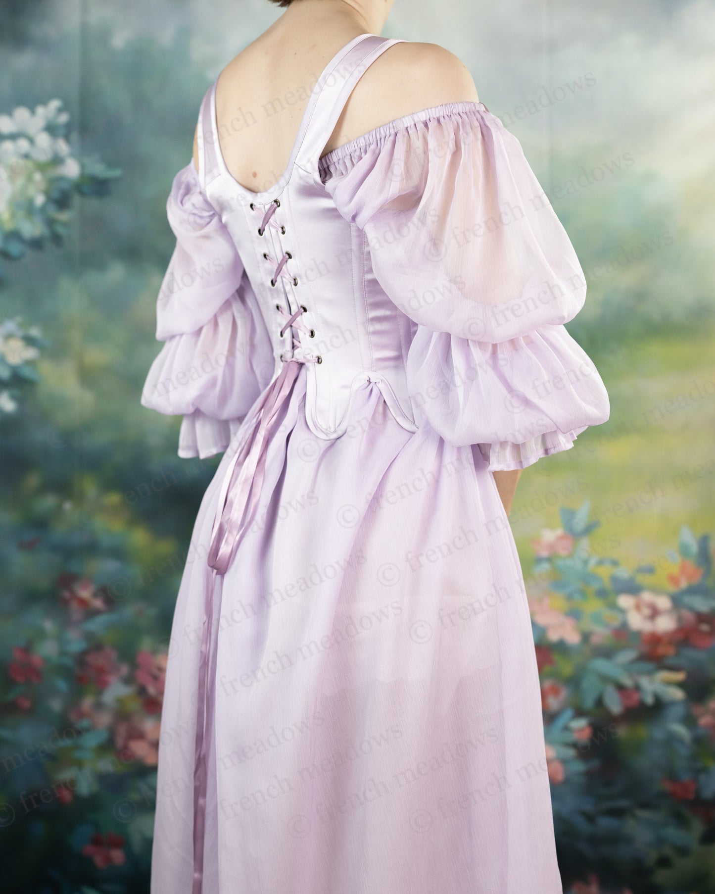 Lilac Satin 18th Century Stays with off-shoulder puff sleeves and back lacing shown in a romantic garden setting