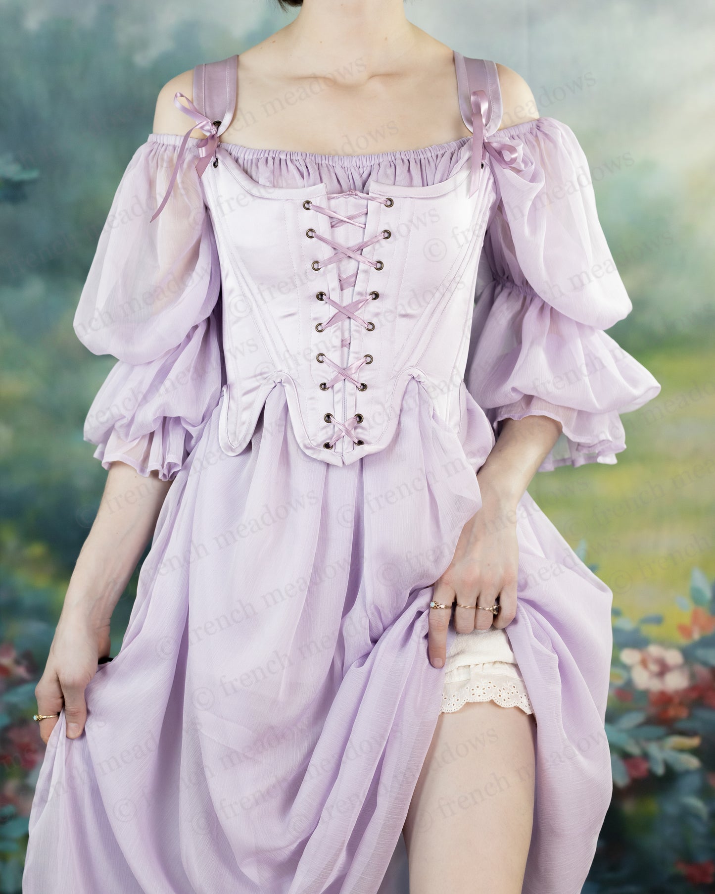 Lilac Satin 18th Century Stays with off-shoulder puff sleeves and front lacing, shown in ethereal outdoor setting against floral backdrop