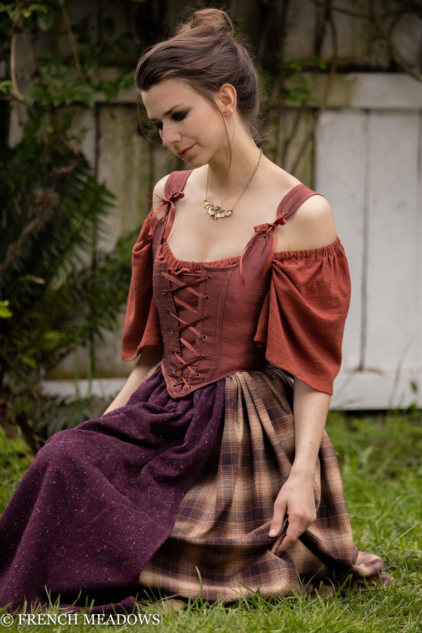 Mary Sanderson Skirt in Brown Plaid shown with purple apron layer and matching rustic corset in outdoor garden setting