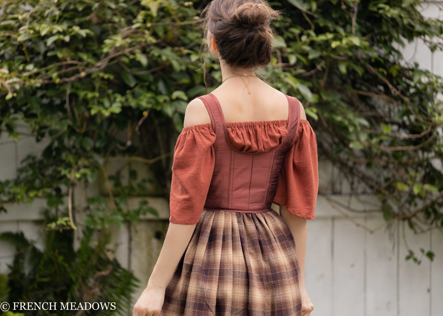 Mary Sanderson Skirt in Brown Plaid with purple apron shown from back view, featuring off-shoulder rust corset top and plaid pattern