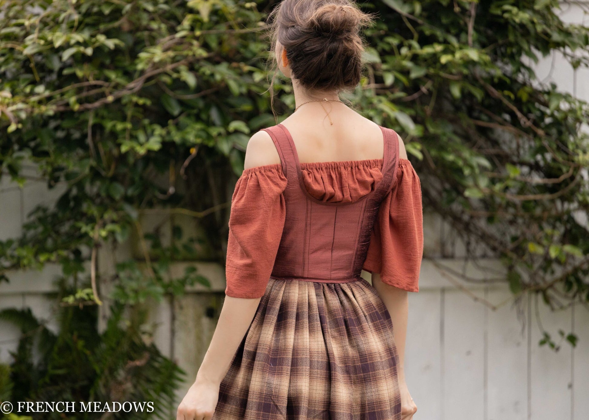 Mary Sanderson Skirt in Brown Plaid with purple apron shown from back view, featuring off-shoulder rust corset top and plaid pattern
