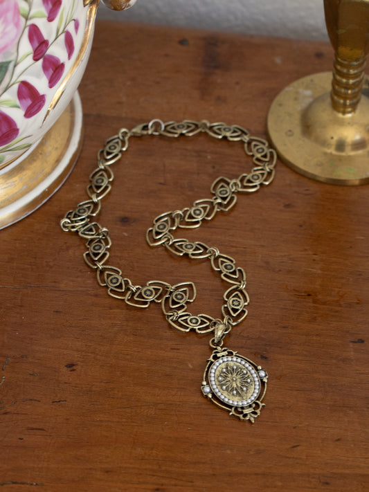 Intricately designed Medieval Pendant Necklace with ornate chain links and detailed circular pendant on wooden surface.