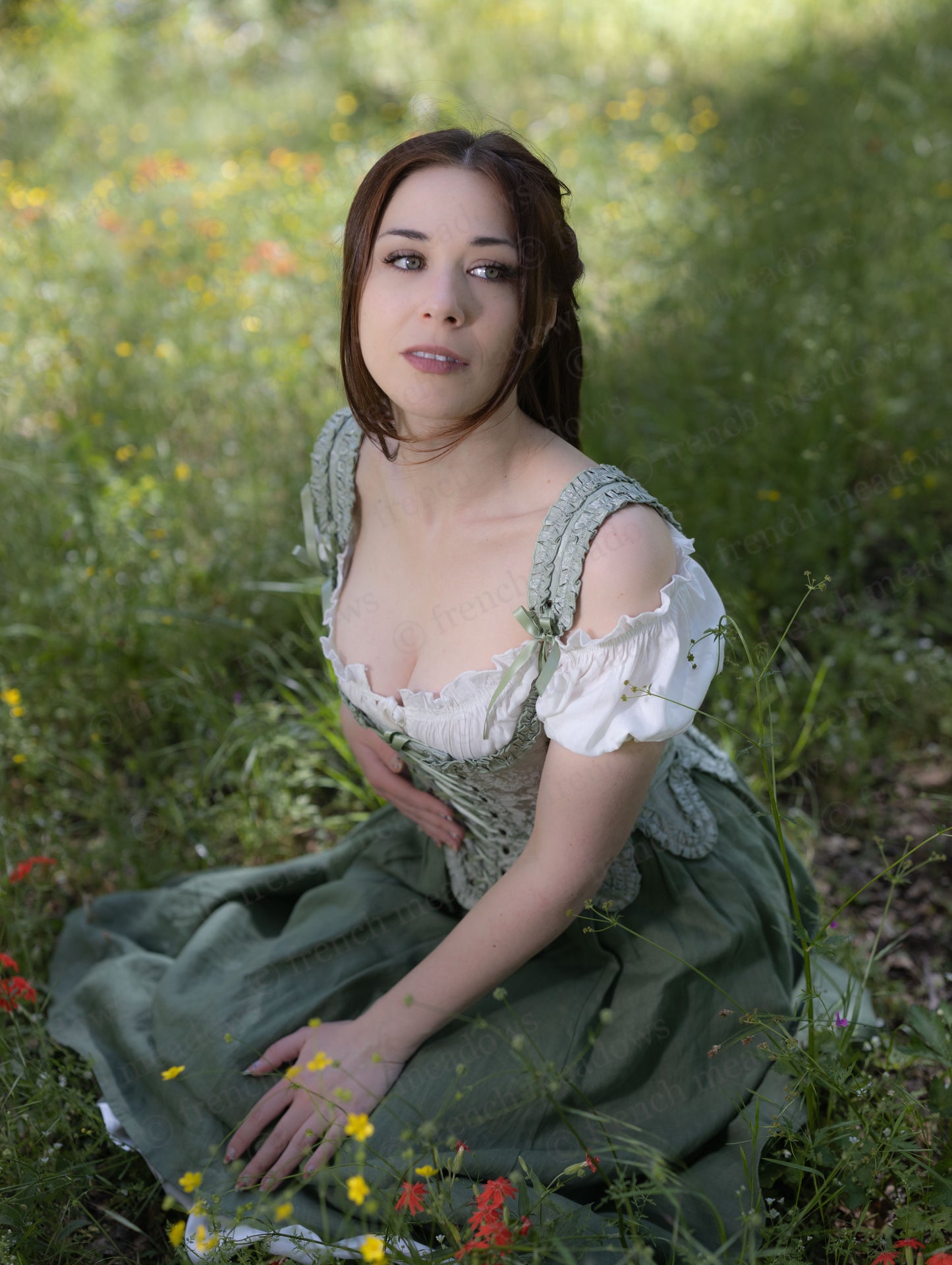 Woman wearing Ivy Green Linen Midi Skirt sitting in a meadow surrounded by wildflowers in soft natural light