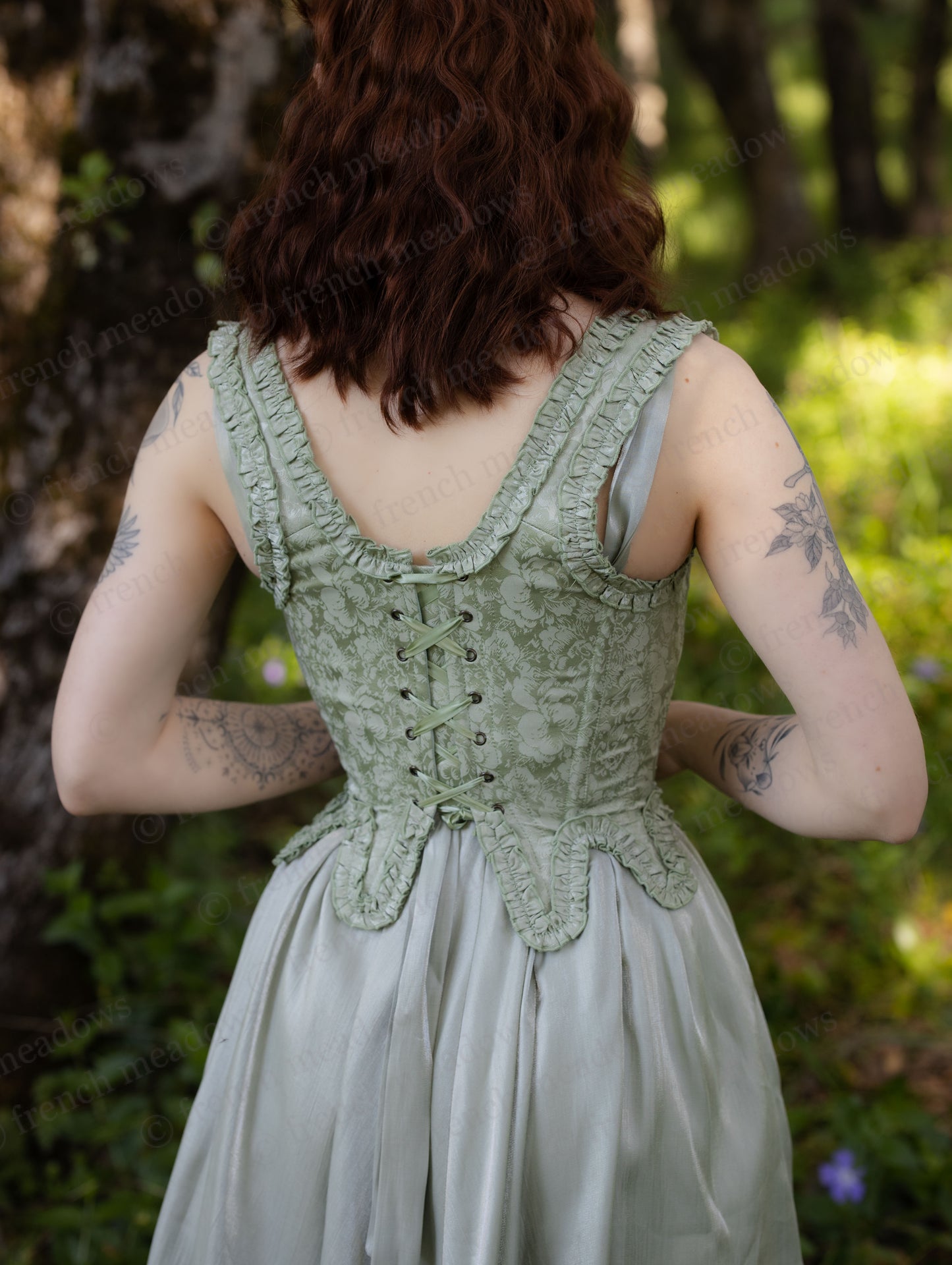 Mint Green Floral 18th Century Stays with ruffle details and back lacing on a woman in a garden setting.