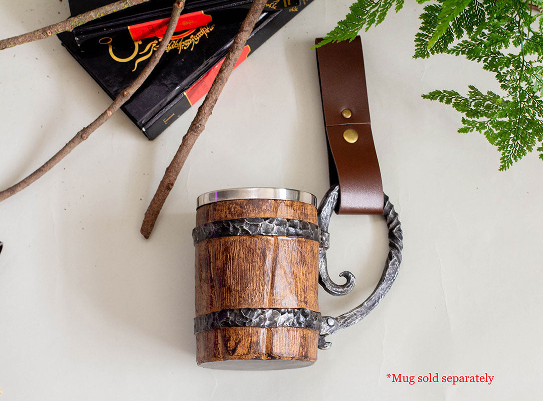 Vegan leather tankard strap with metal snap shown attached to wooden medieval drinking mug on beige background