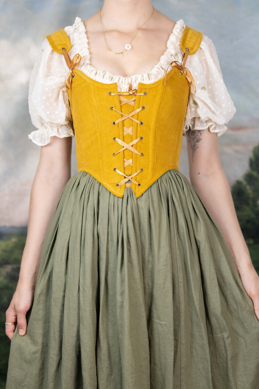 Handmade Mustard Corduroy Renaissance Corset worn over a white puff sleeve blouse and paired with a high-waisted olive skirt