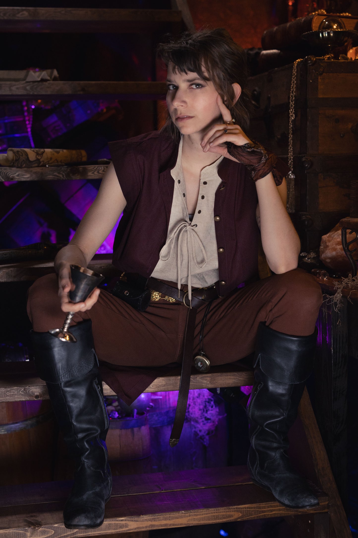 Linen Sleeveless Pirate Tank shown with brown pants and boots in rustic setting with purple lighting and wooden crates