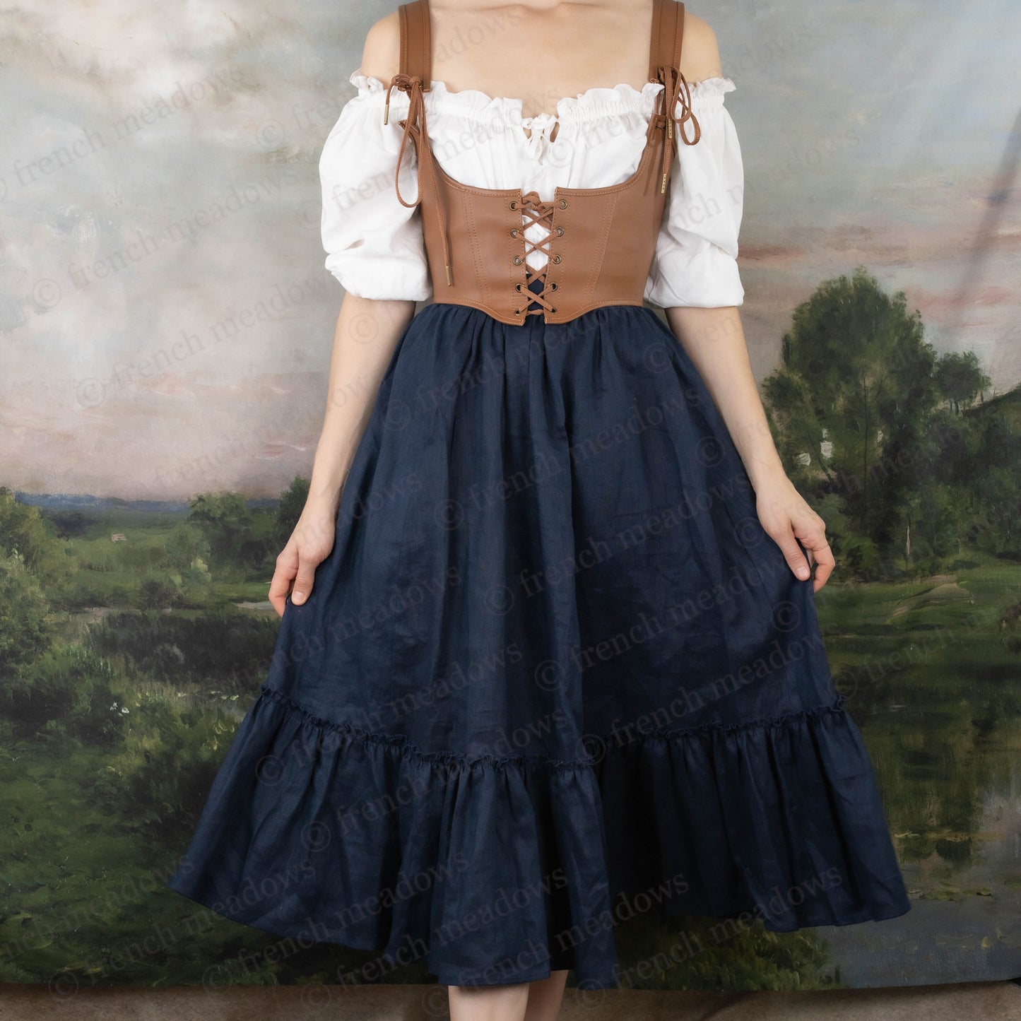 Brown leather underbust corset belt worn over white peasant blouse and navy blue ruffled skirt in Renaissance-inspired style