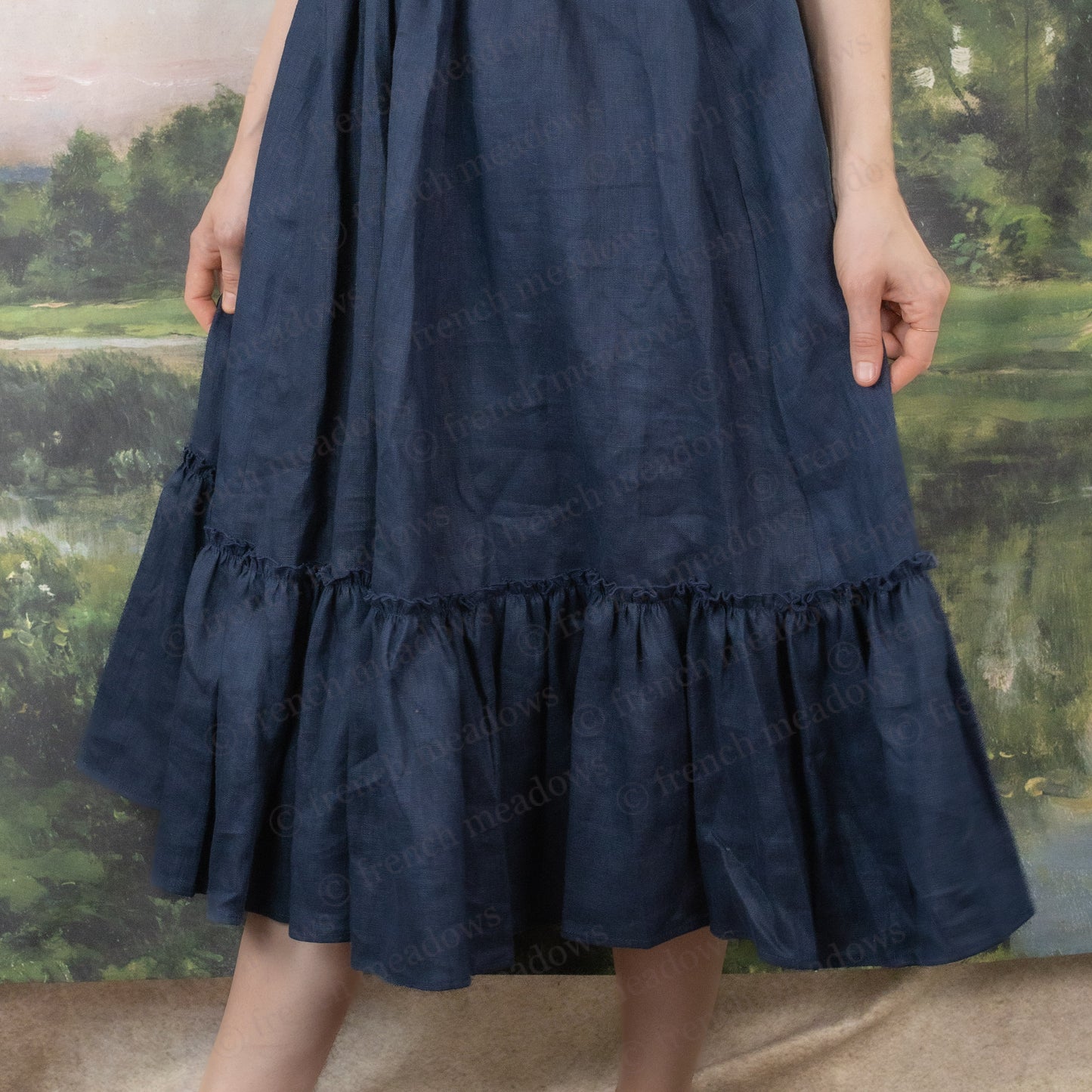 Navy blue linen midi skirt with ruffle hem and elastic waistband shown against nature backdrop