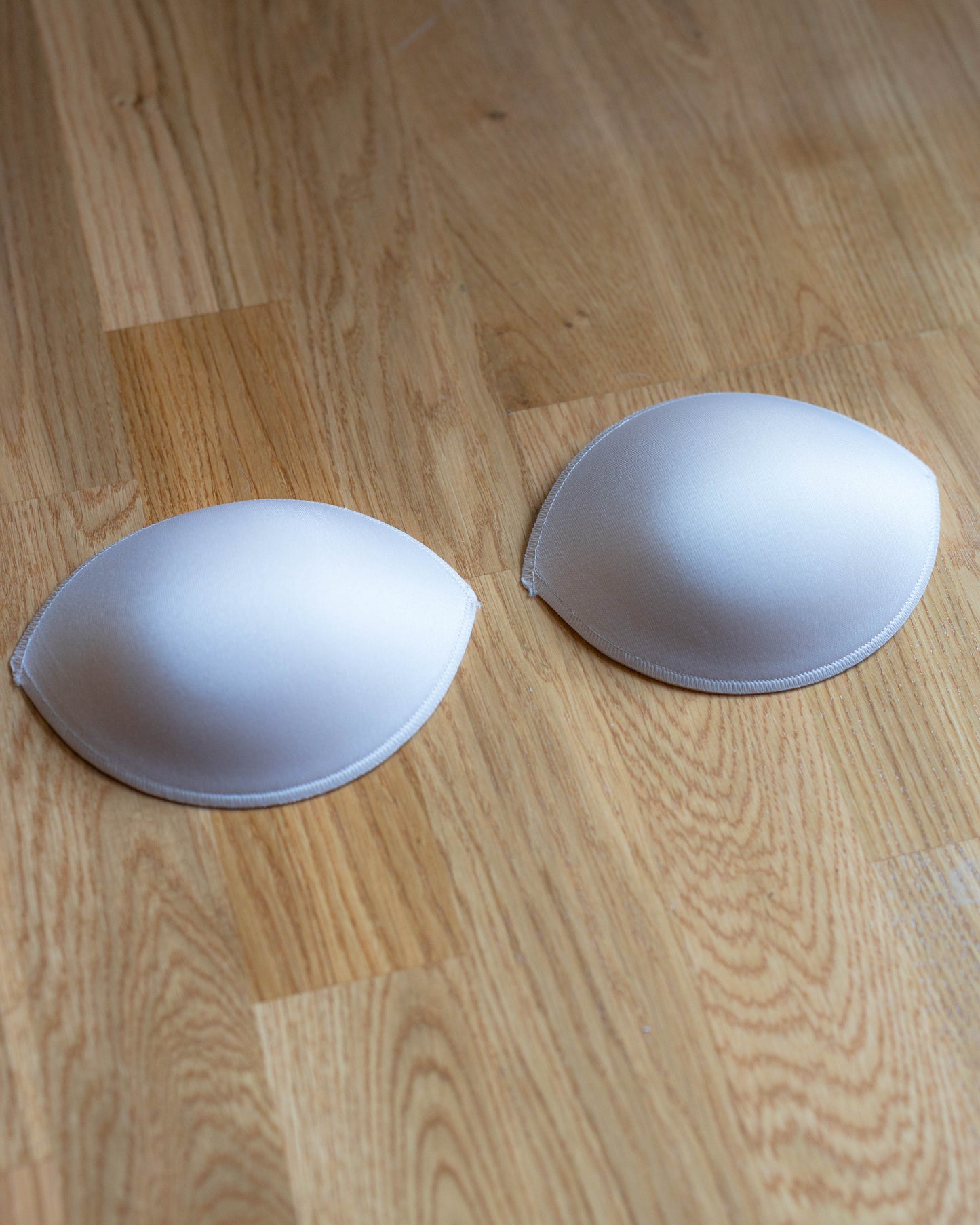 Padded Bra Cups shown on wooden floor, designed to enhance cleavage or fill in space for smaller A and B cup sizes.