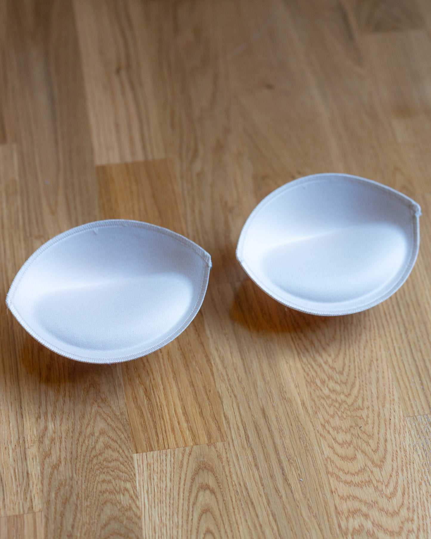 Padded Bra Cups shown on wooden surface designed to enhance cleavage and fill space under corsets for smaller cup sizes.
