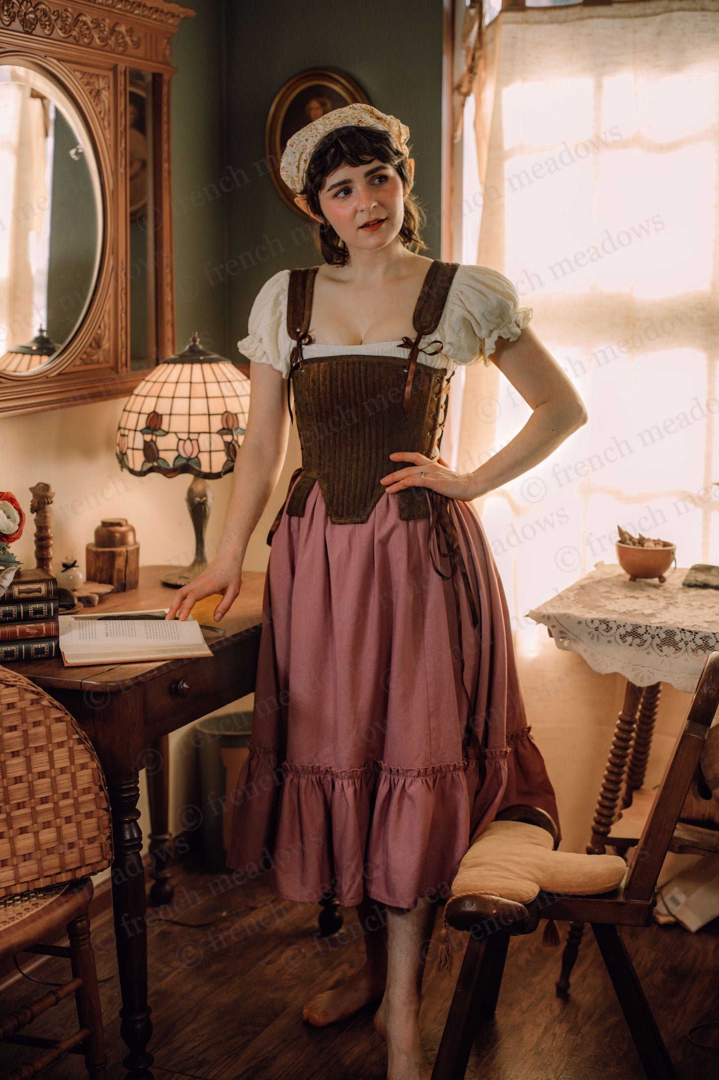 Mauve linen ruffle skirt styled with brown corset and white peasant blouse in vintage cottage setting with antique furniture