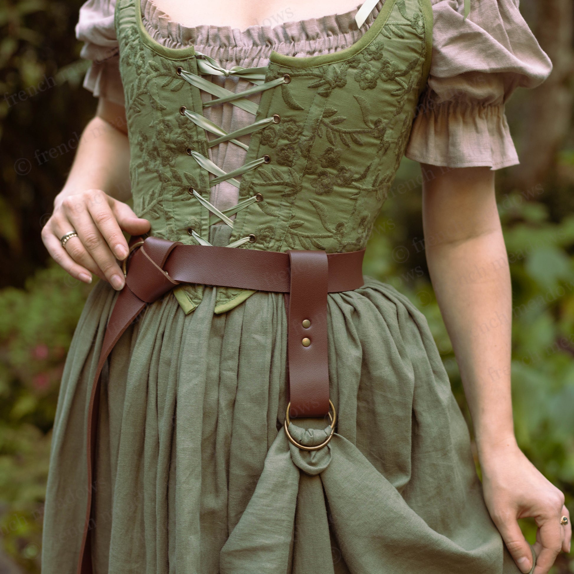 Vegan leather skirt hike shown on brown belt with D-rings, attached to green renaissance dress showing gathering detail