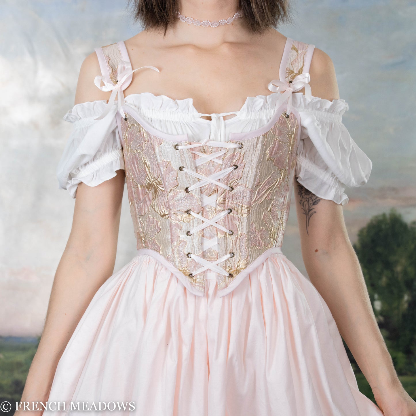 Pink and metallic gold floral Renaissance bodice with white peasant sleeves, lace-up front, and scooped neckline shown on form