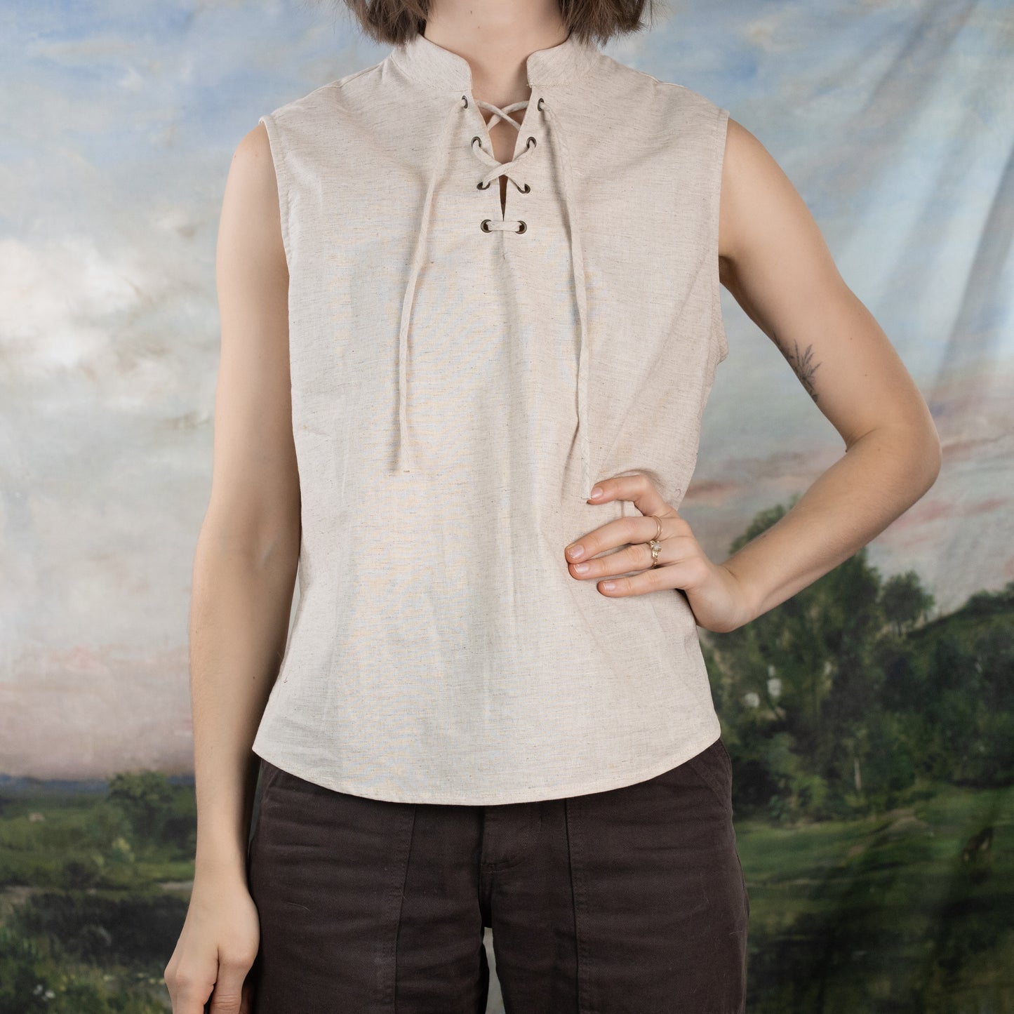 Linen Sleeveless Pirate Tank in natural heather with lace-up neckline shown against pastoral background