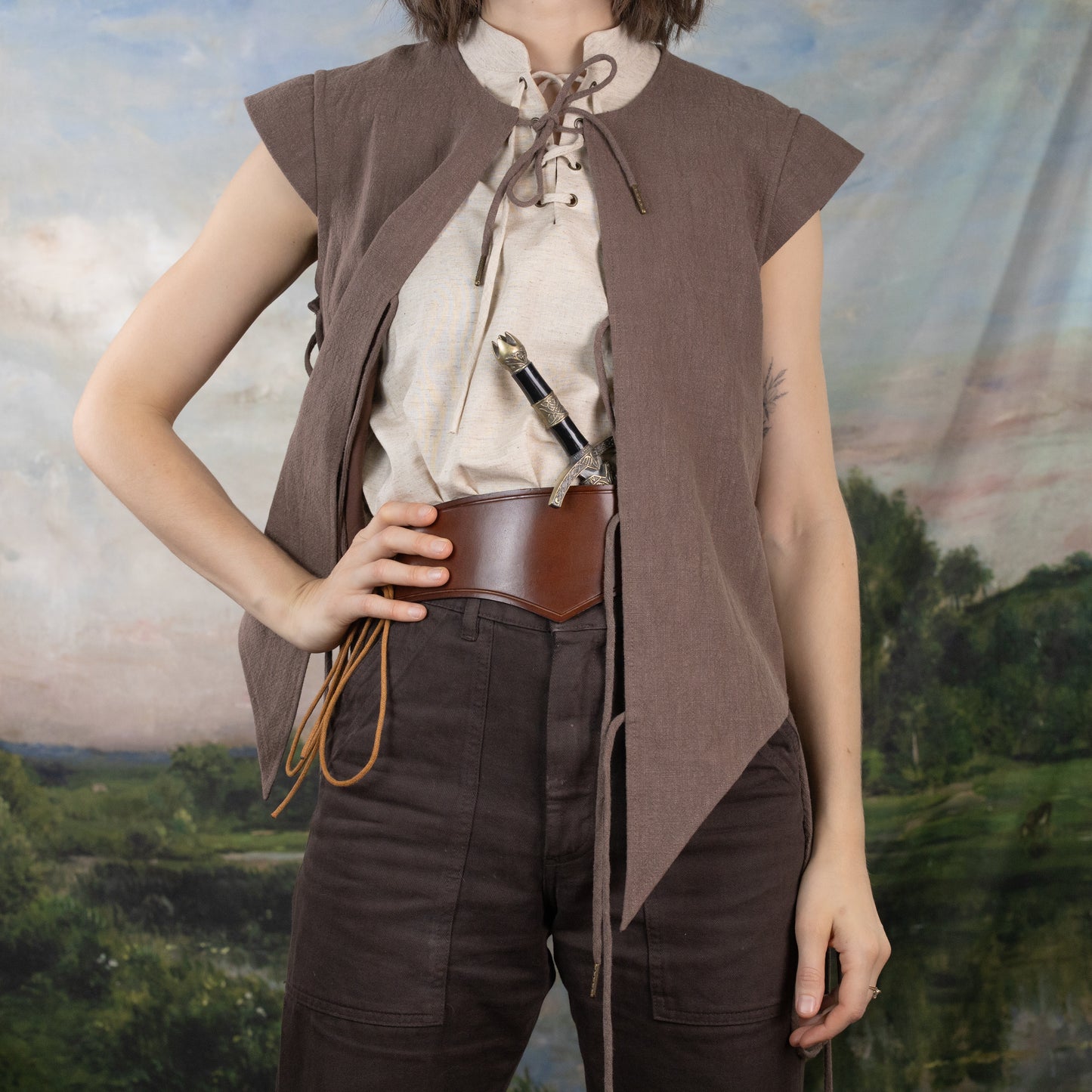 Linen Sleeveless Pirate Tank shown with lace-up neckline and rustic heather fabric, styled with brown vest and leather accessories