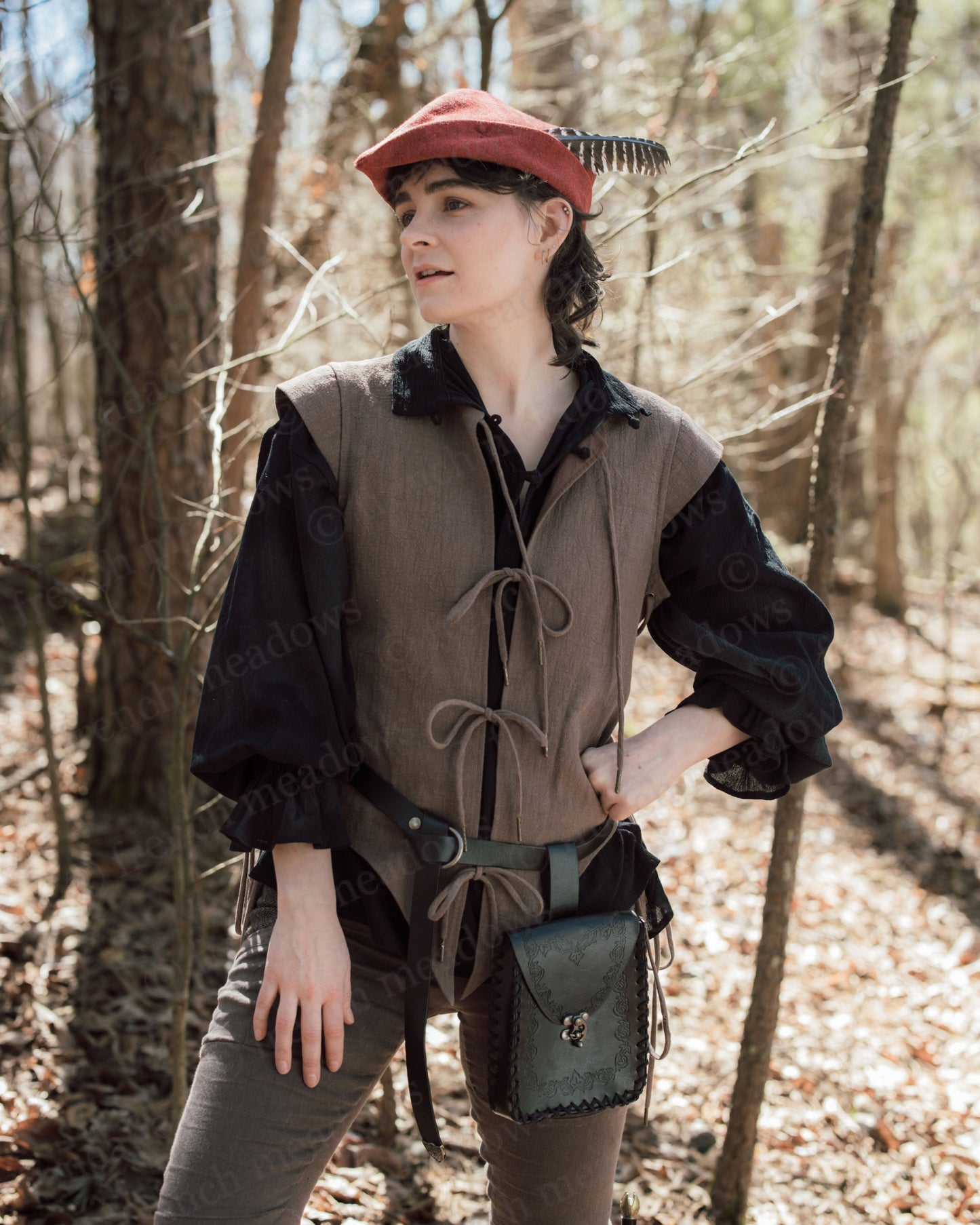 Brown Bard Vest shown in woodland setting with lace-up front detail, styled with black shirt and red cap for renaissance costume look
