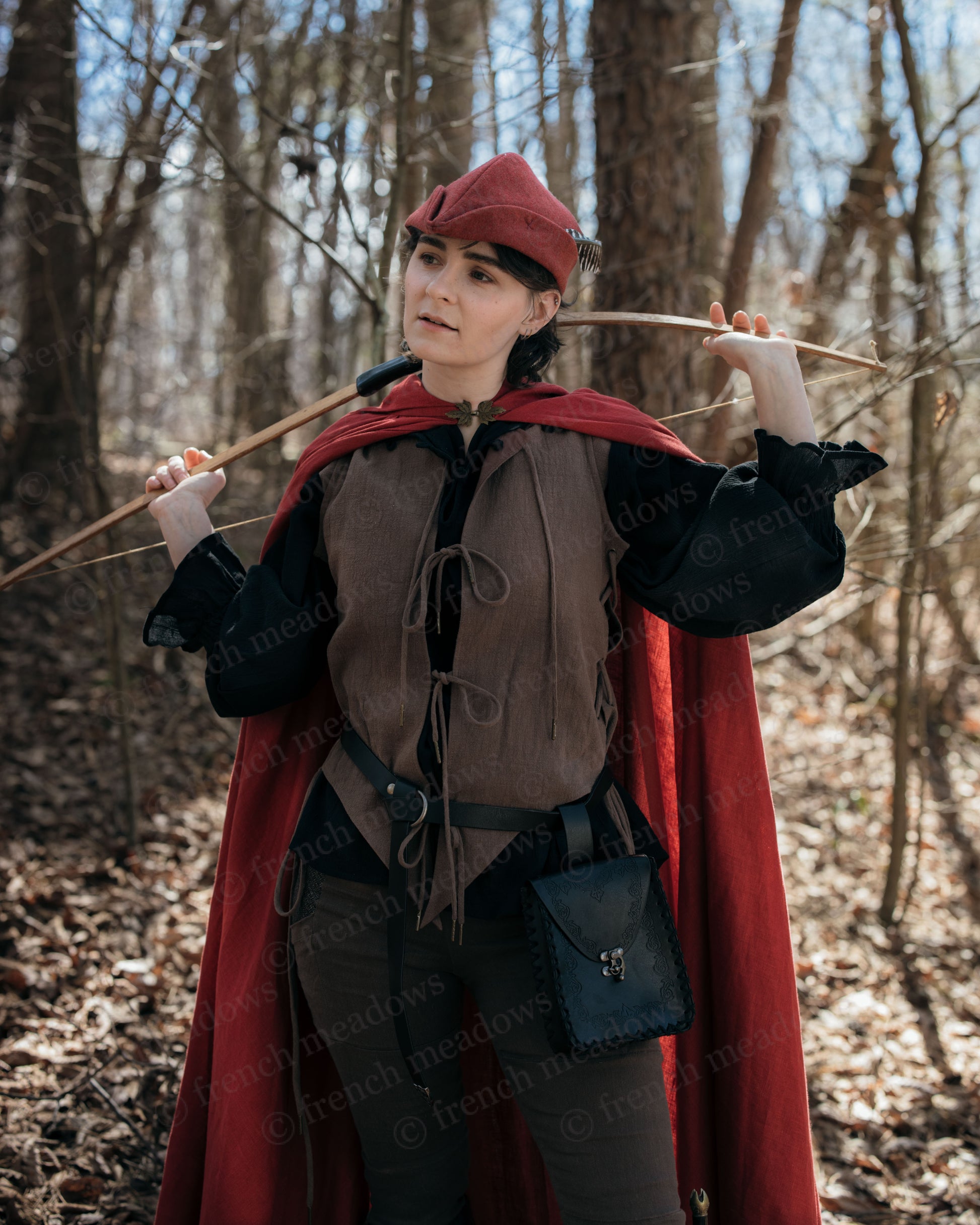 Brown Bard Vest worn with red cloak and cap in forest setting, medieval renaissance costume with front ties and adjustable lacing