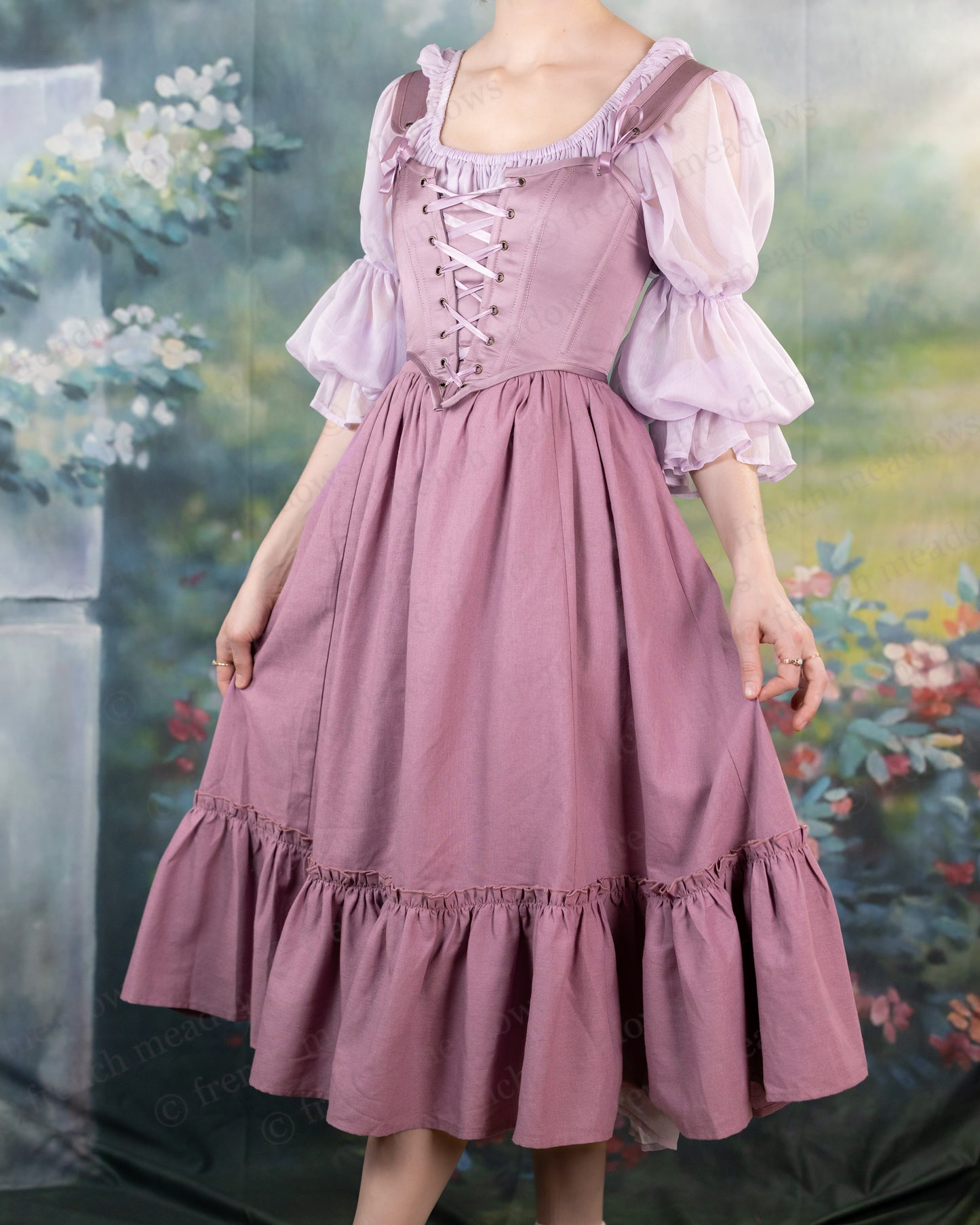 Mauve linen ruffle skirt with corset-style bodice, puff sleeves, and flowing ruffled hem, displayed against garden backdrop
