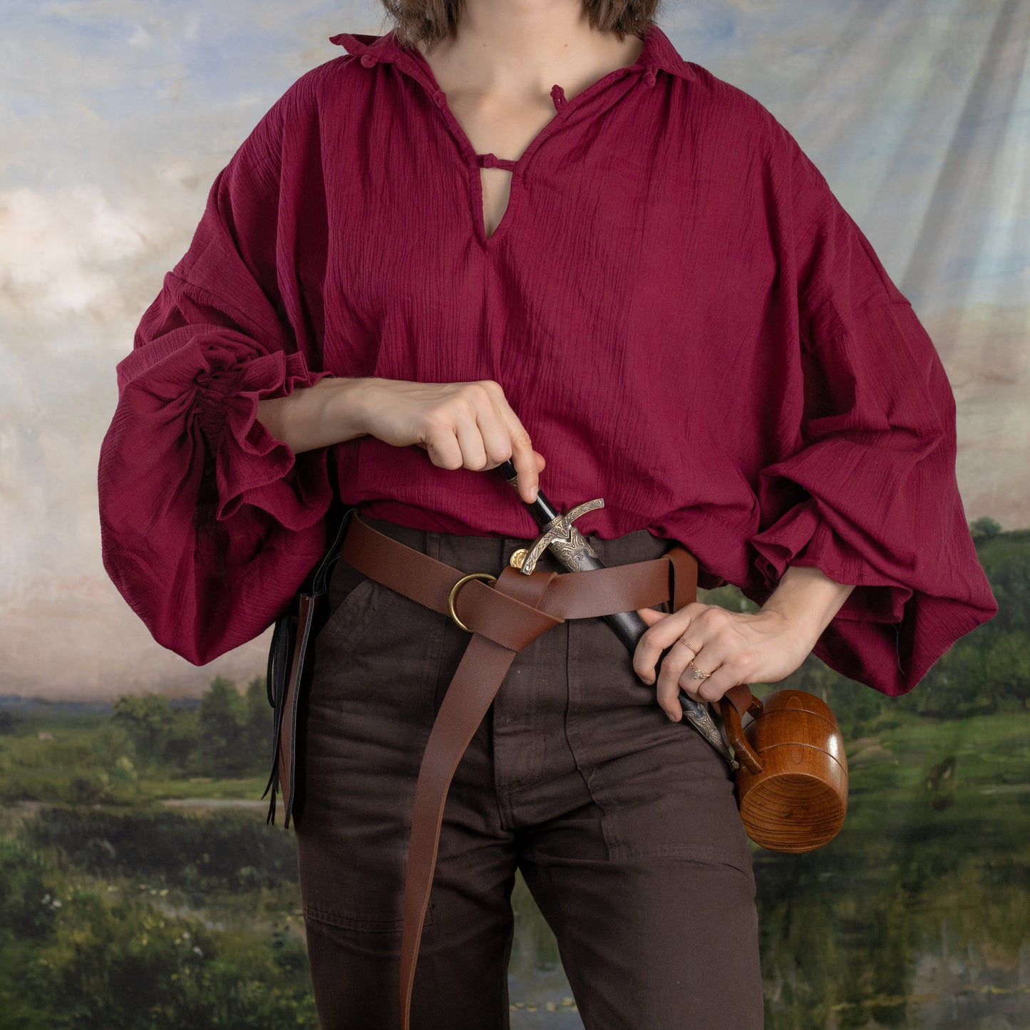 Darcy Shirt in deep burgundy with billowing sleeves and traditional tie neckline, styled with brown leather belt and pants