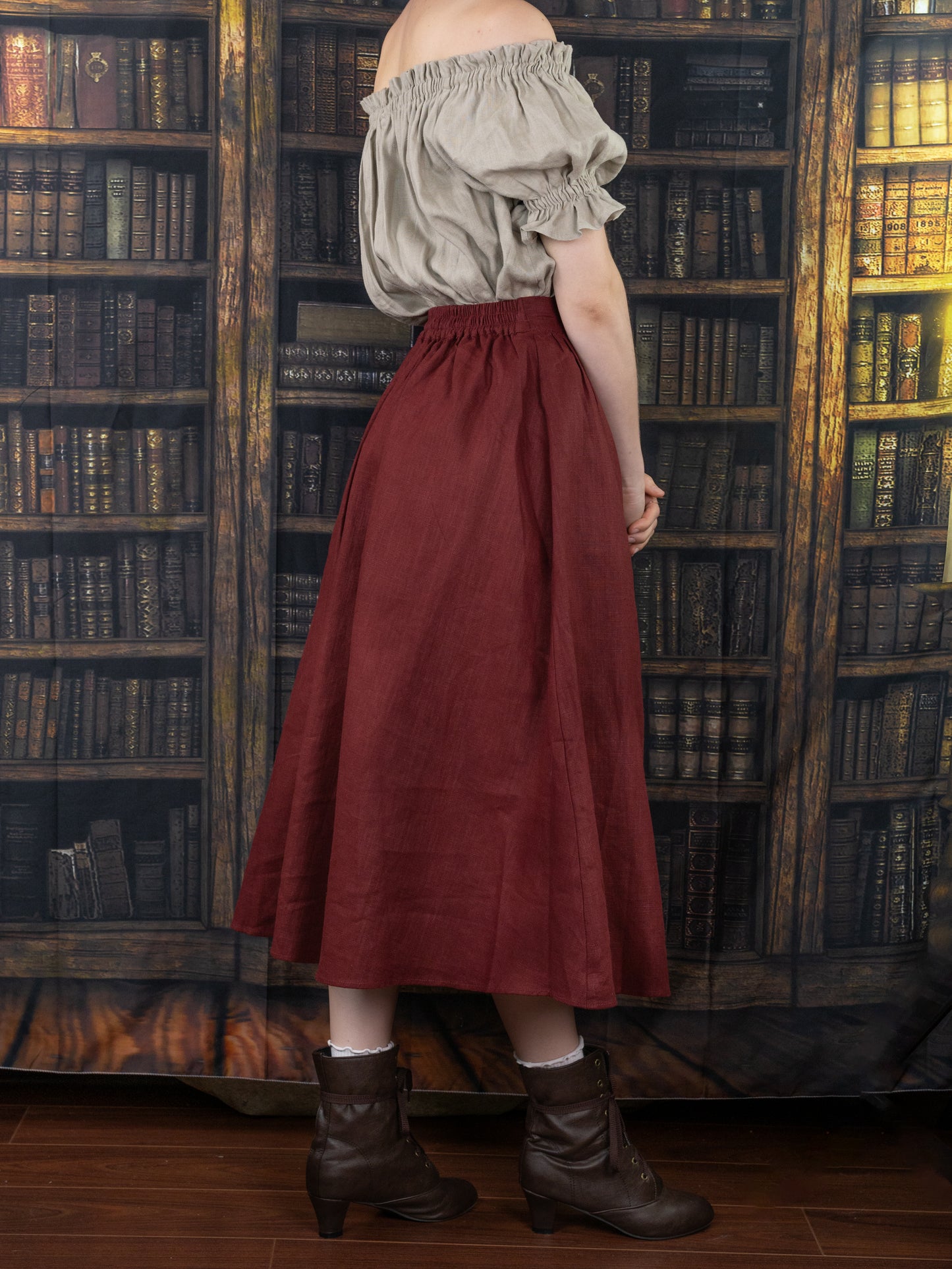 Burgundy Ramie Midi Skirt shown in library setting, styled with gray peasant top and brown boots, against vintage bookshelf backdrop