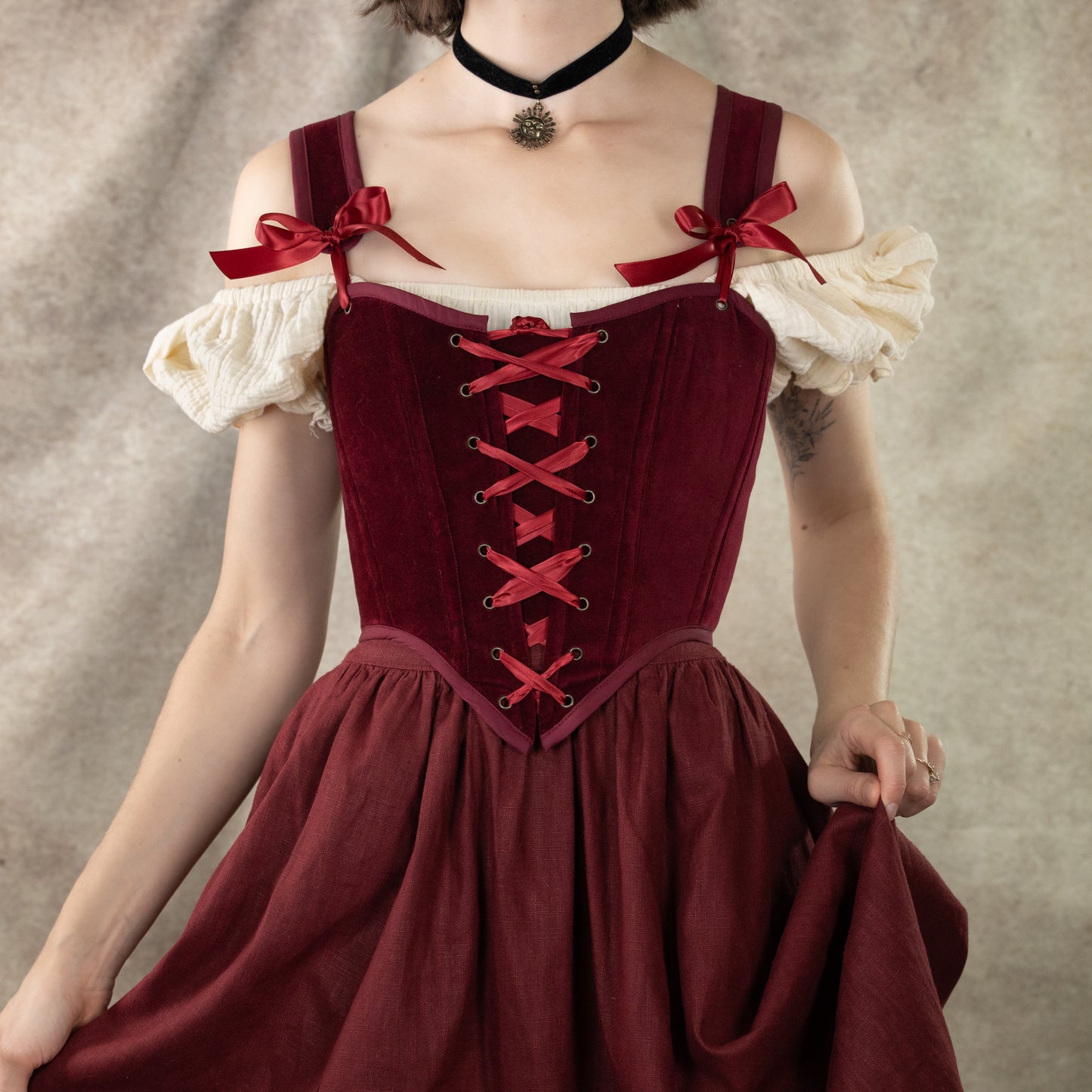 Dark red velvet corset top with lace-up front, off-shoulder puff sleeves, and bow straps in renaissance style