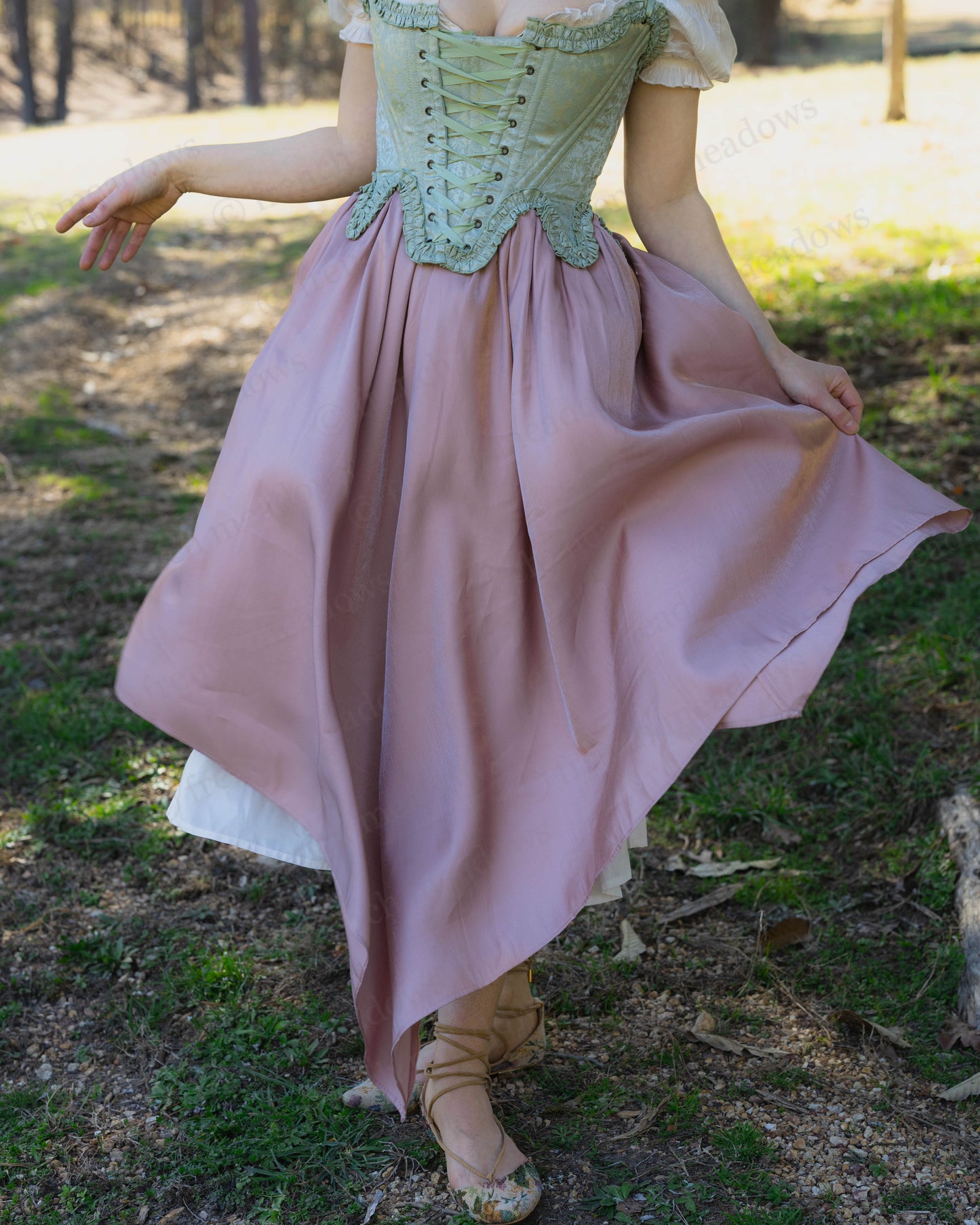 Woman outdoors wearing a pink handkerchief hem dress with a green corset, Flutter Fairy Dress style.